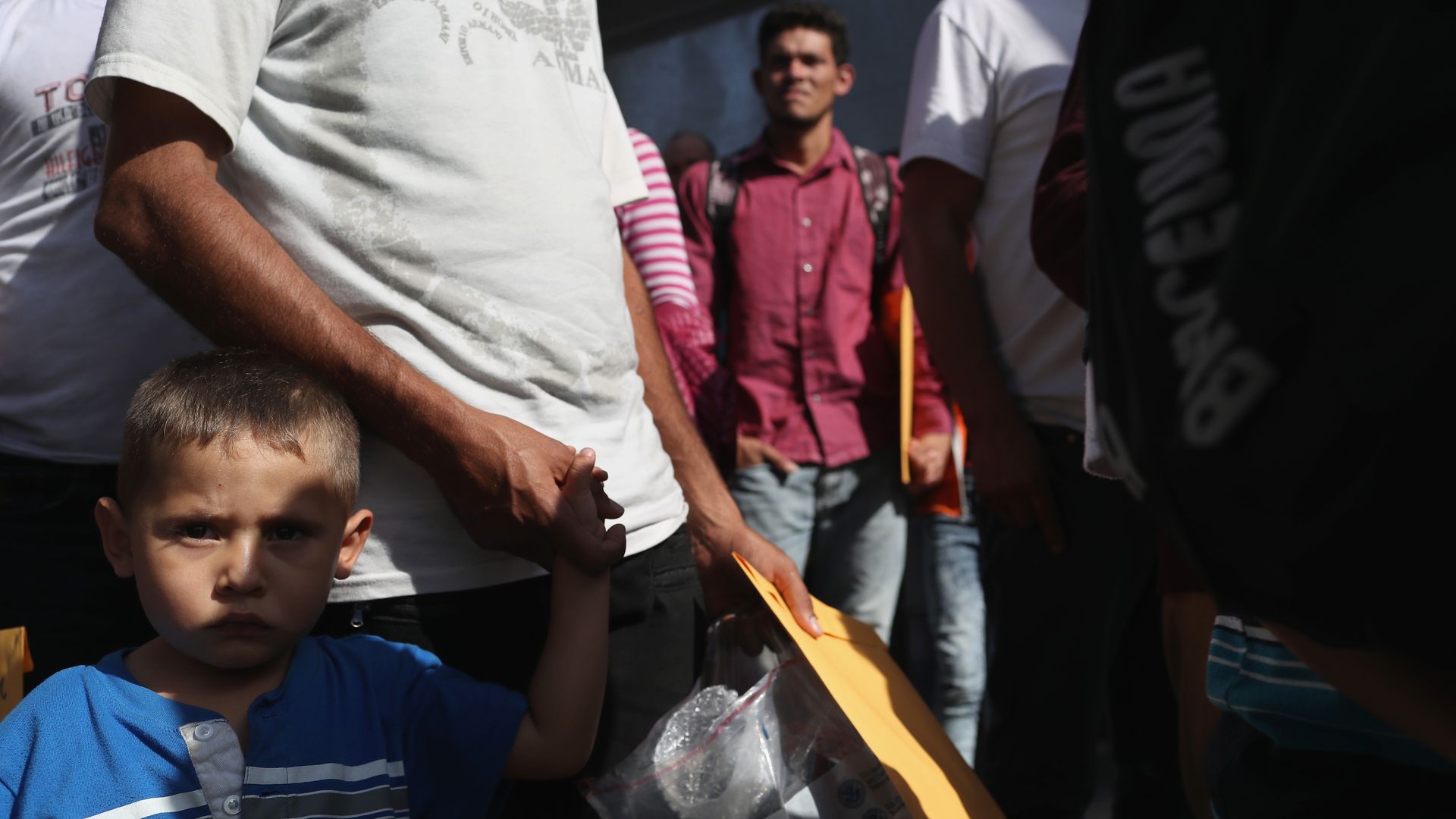 A young boy holds a man's hand. 