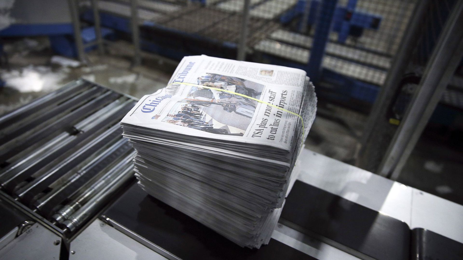 photo of a stack of newspapers coming off printing press. 