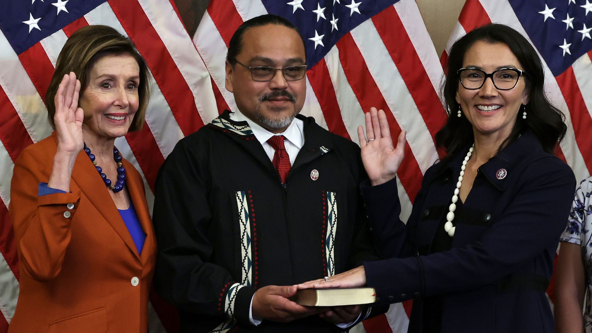 Photo of Mary Peltola raising her right arm as she's sworn in by Nancy Pelosi