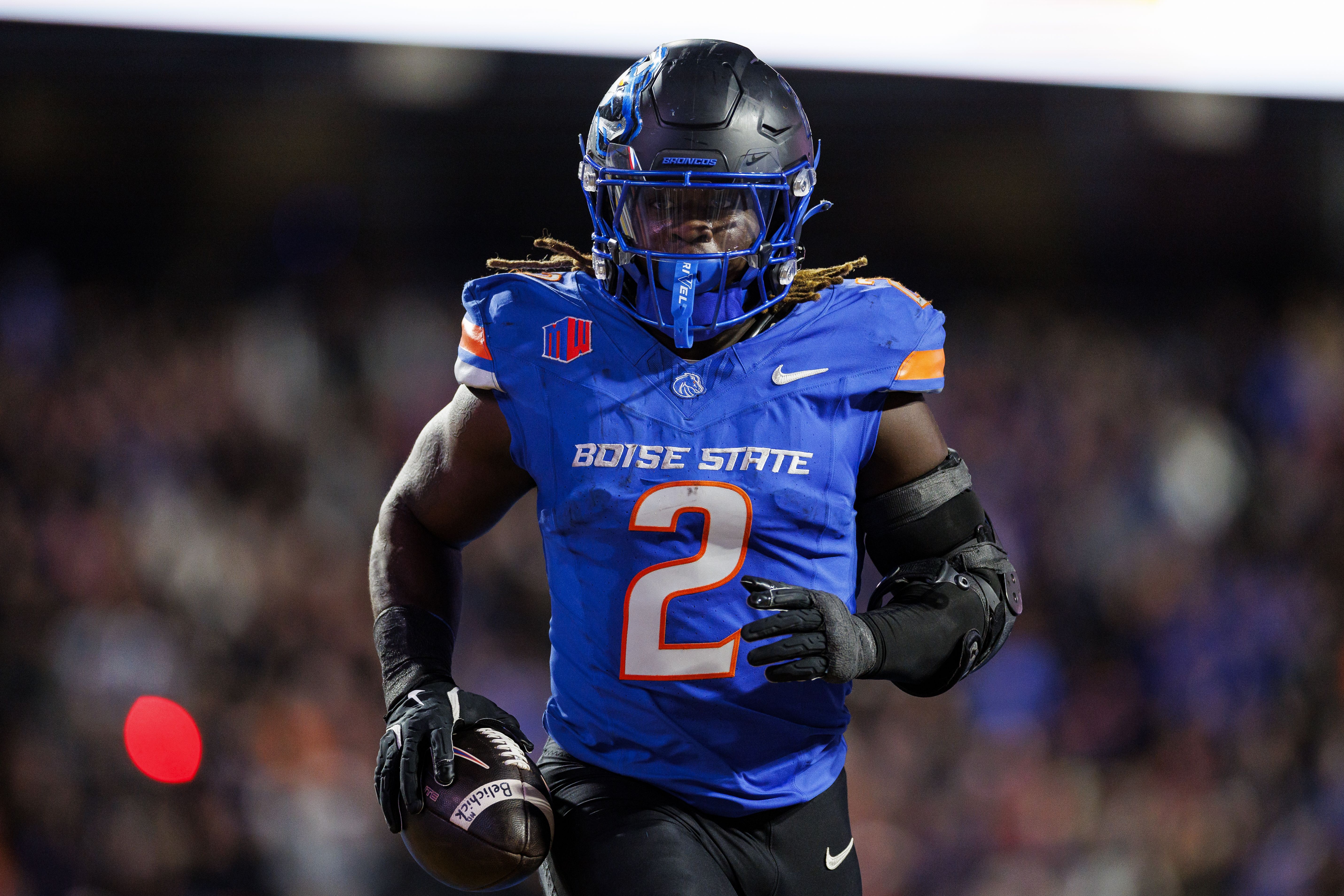 Photo of a football player in uniform running on a field.