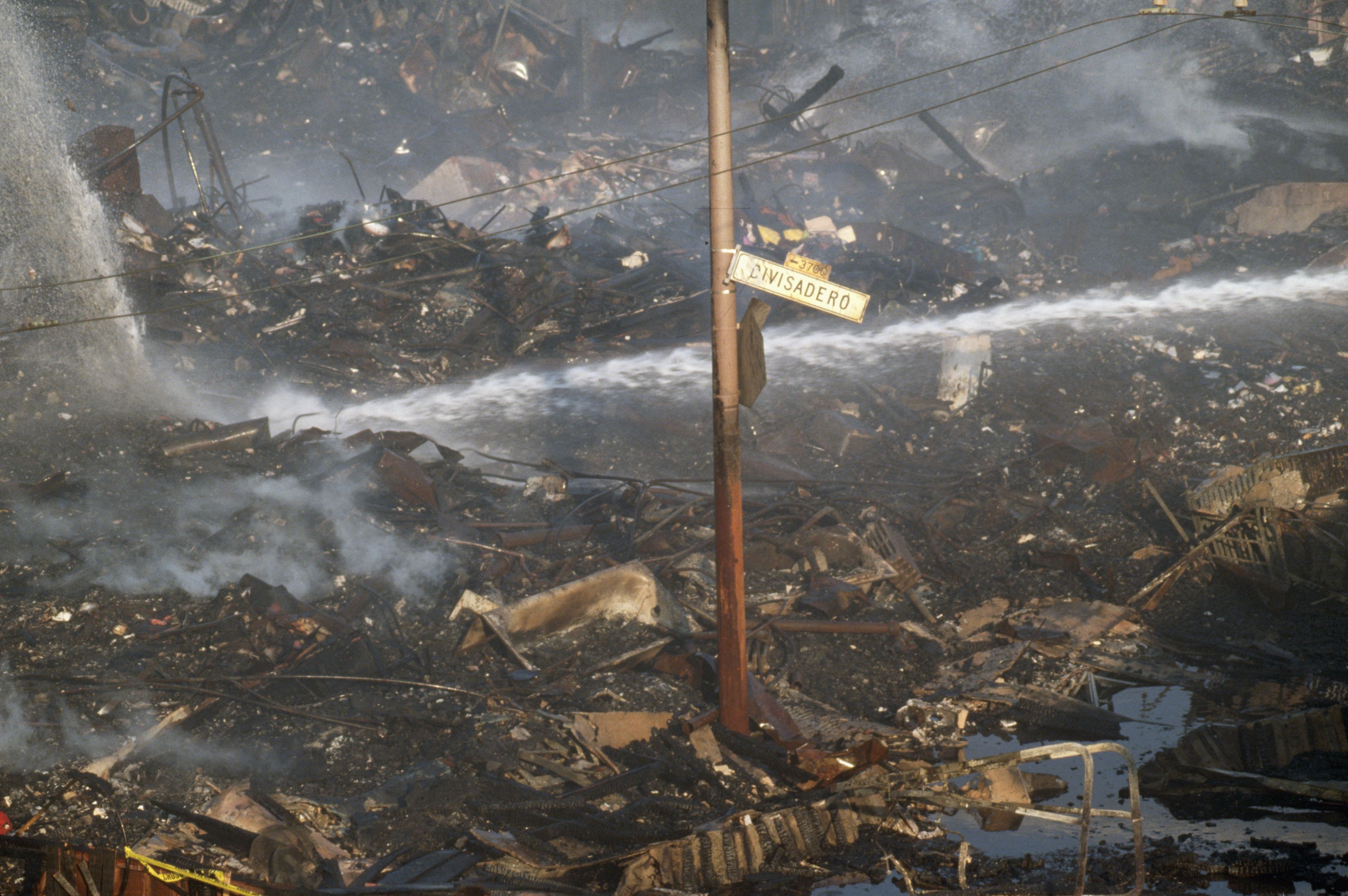 Photo of charred debris surrounding a street sign that says "Divisadero" 