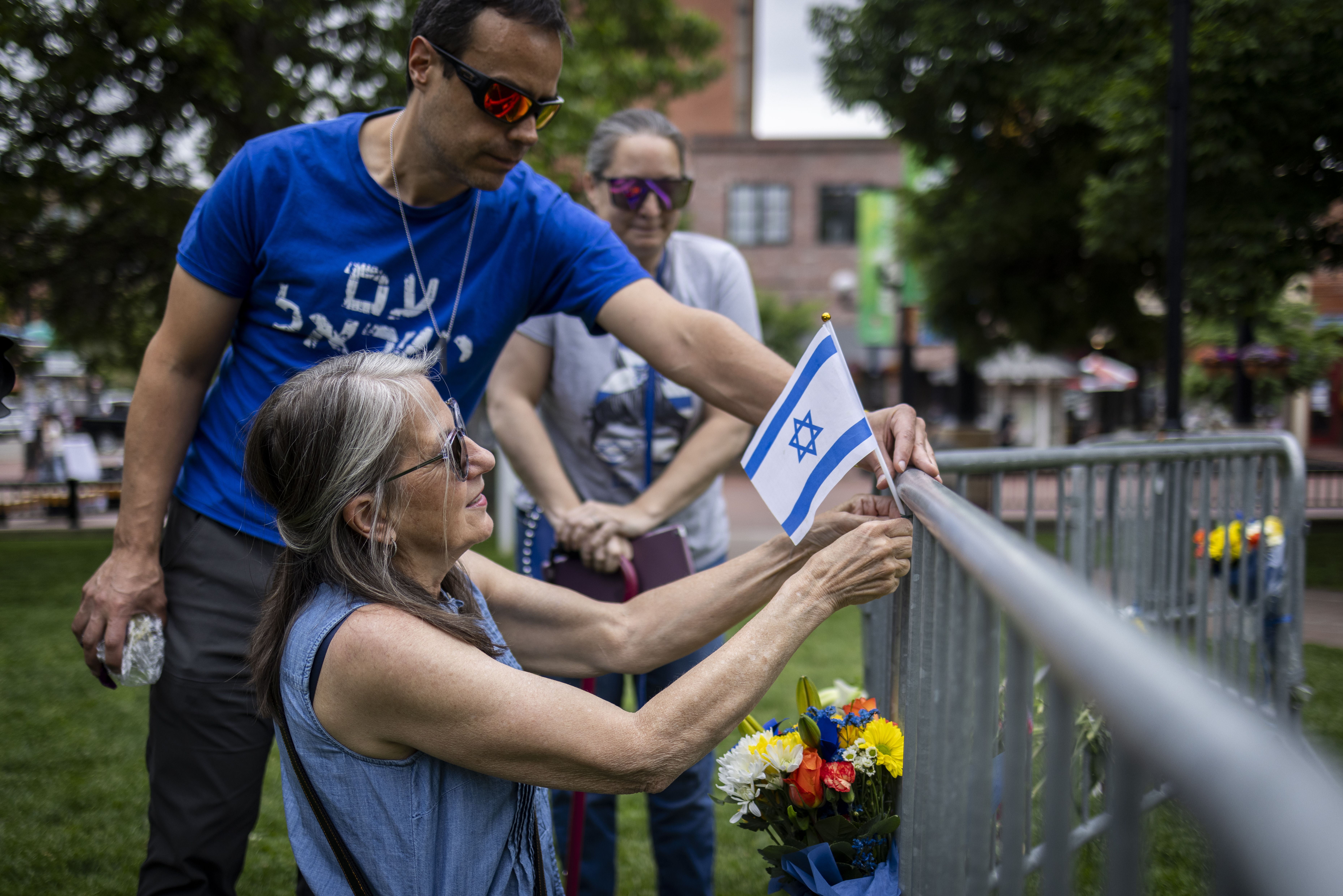 A woman lays flowers and a flag at the site of Sunday's attack outside the Boulder County Courthouse.