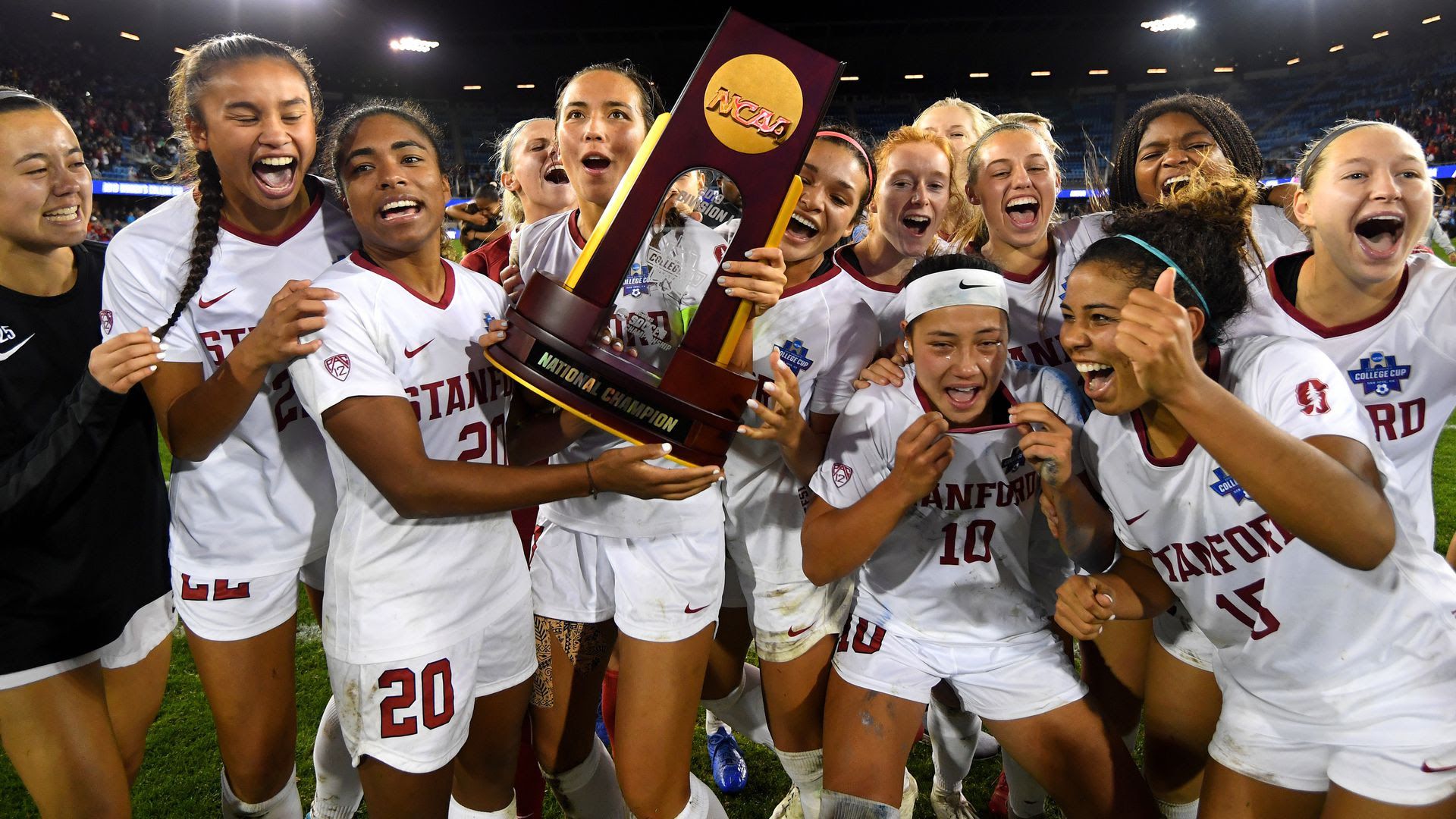 College soccer players holding a trophy.