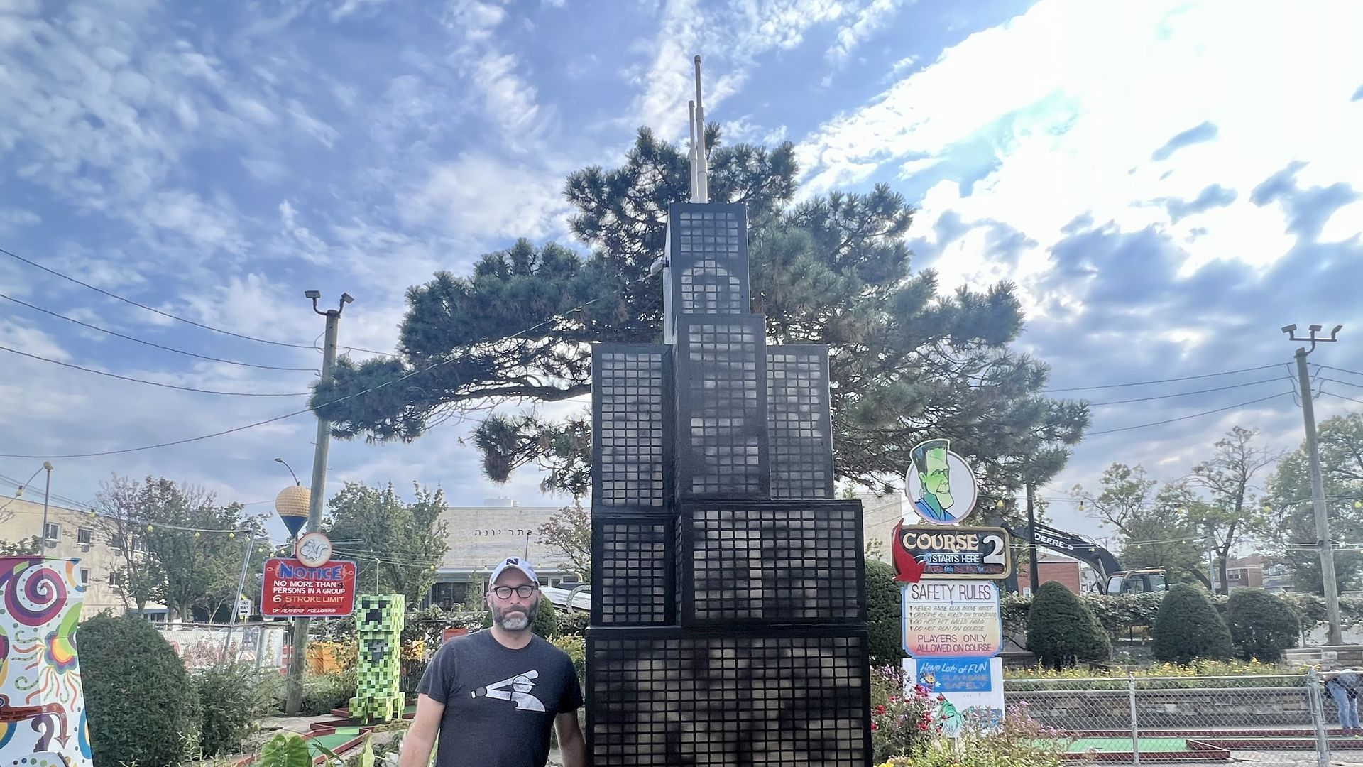 Man standing next to a replica of the Sears Tower. 