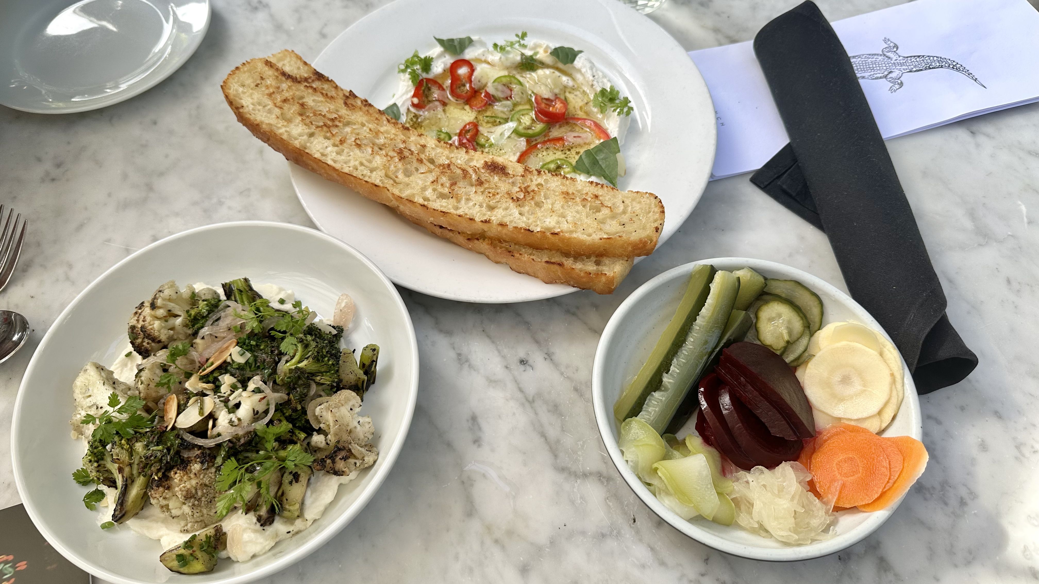 Photo shows plates of goat cheese dip, a broccoli salad and a pickle plate.