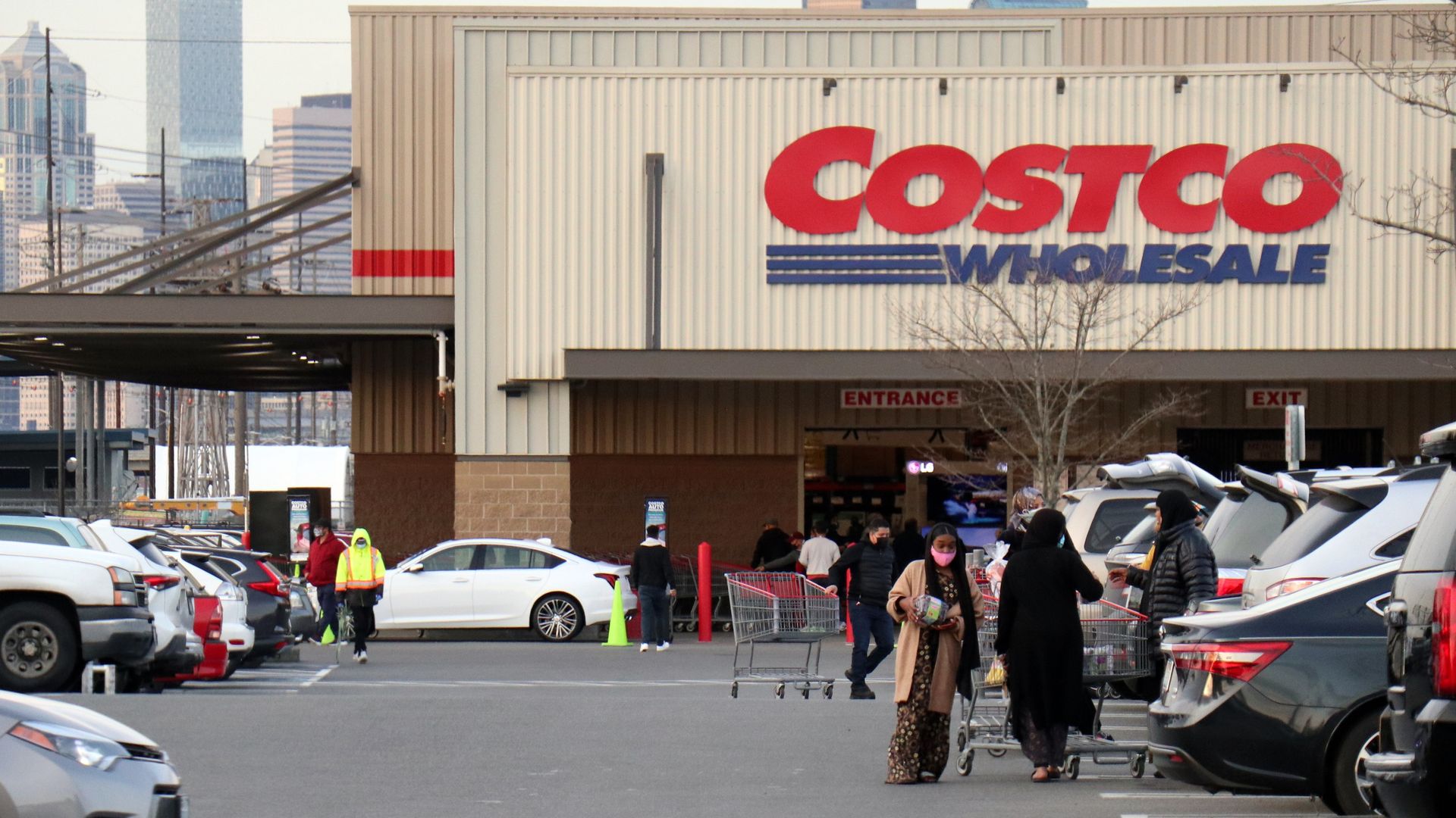 Costco storefront with shoppers in parking lot with cars nearby