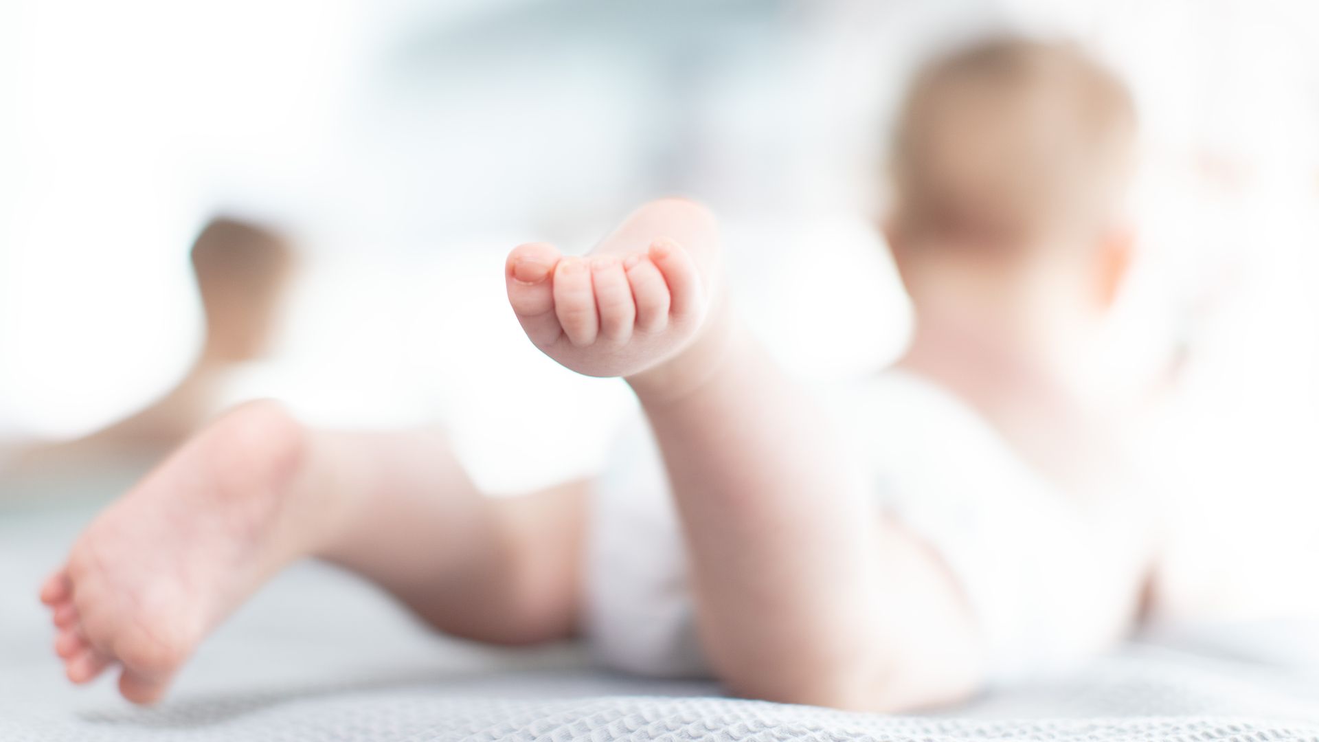 A baby wearing a diaper crawls