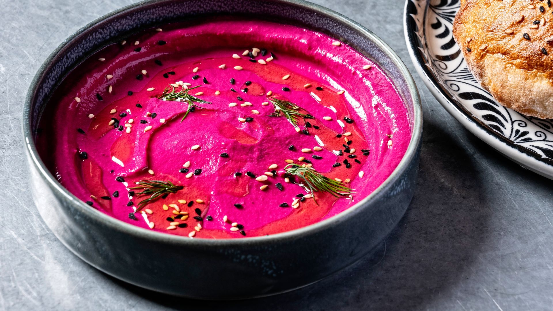 A bright purple beet and yogurt dip topped as dill with a round flatbread