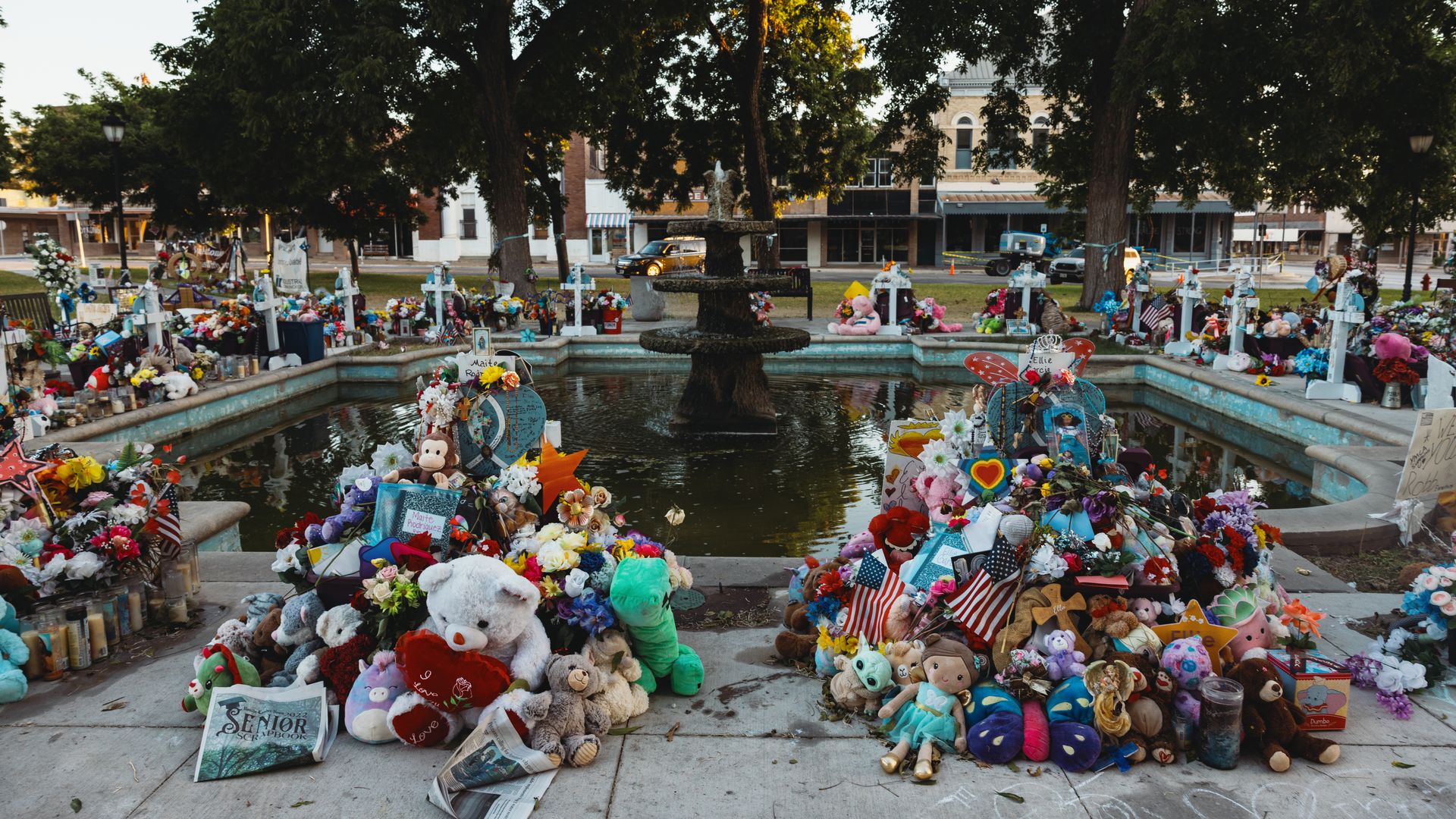 stuffed animals, flowers, and other keepsakes are left next to crosses bearing the names of the victims of the mass shooting at Robb Elementary School