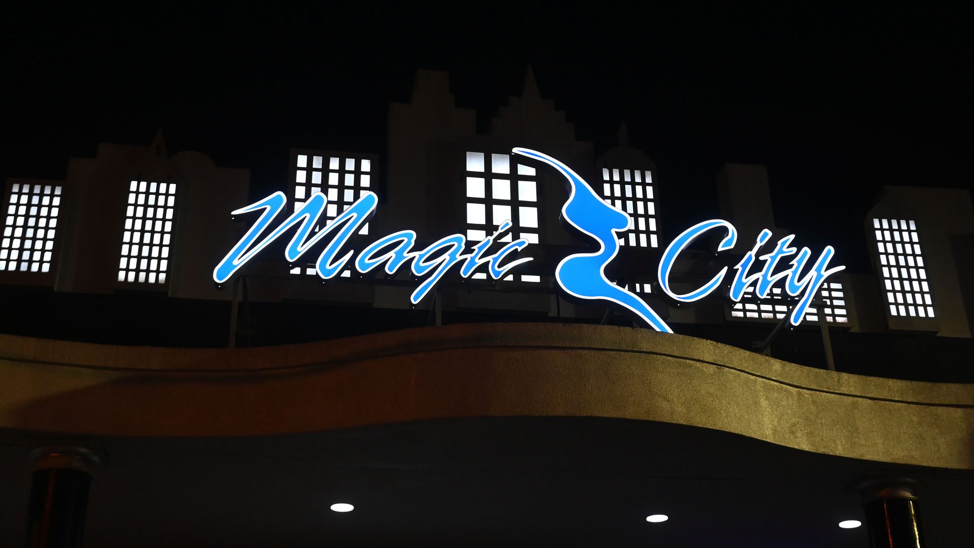 A sign above a business entrance with the words "Magic City" written in blue, cursive writing. 