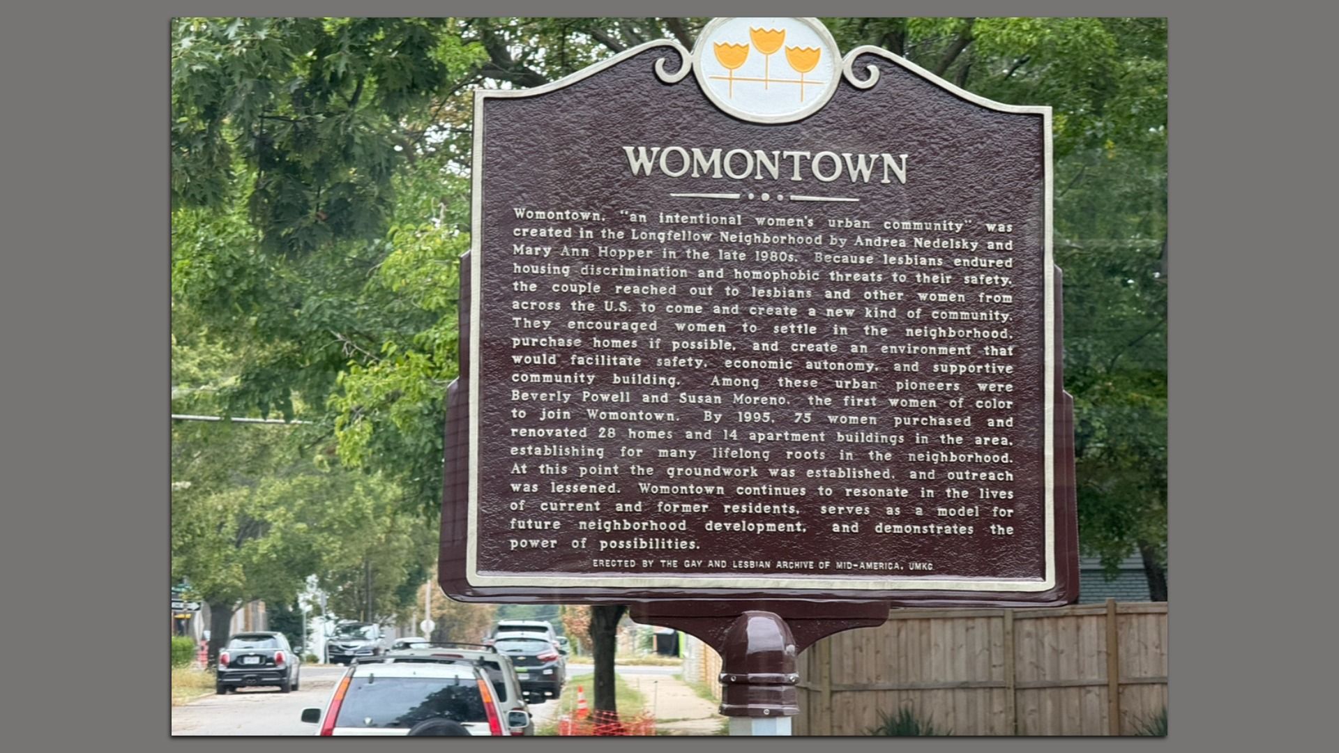 Brown historical marker titled "WOMONTOWN" describing the creation of a women's urban community in the 1980s Longfellow Neighborhood to support lesbians and women through safety and housing.