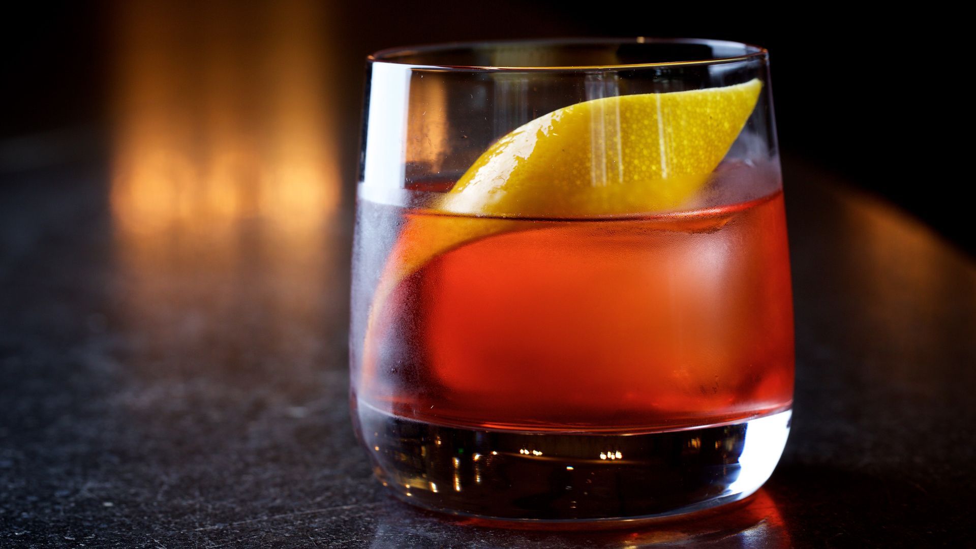 A negroni with a citrus peel on a dark background