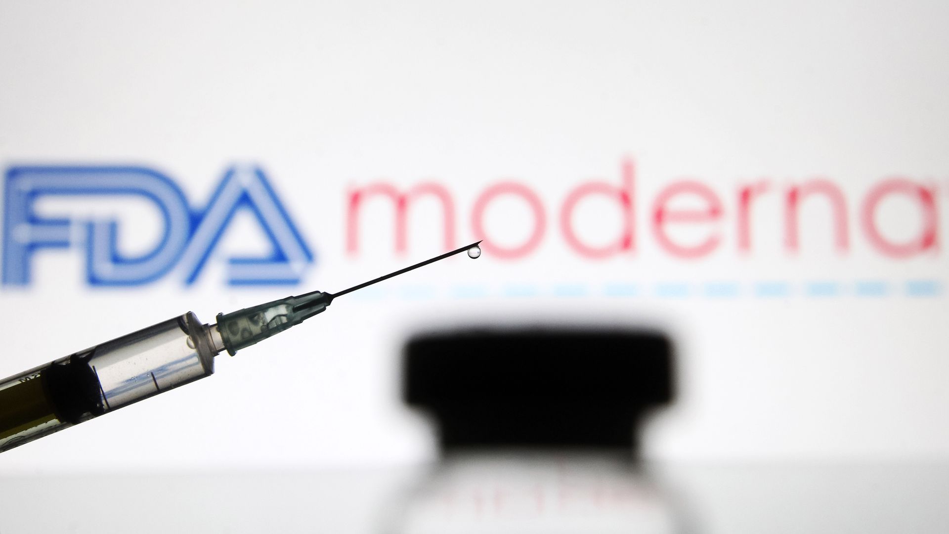Picture of a vaccine syringe in front of the Moderna logo and the FDA logo