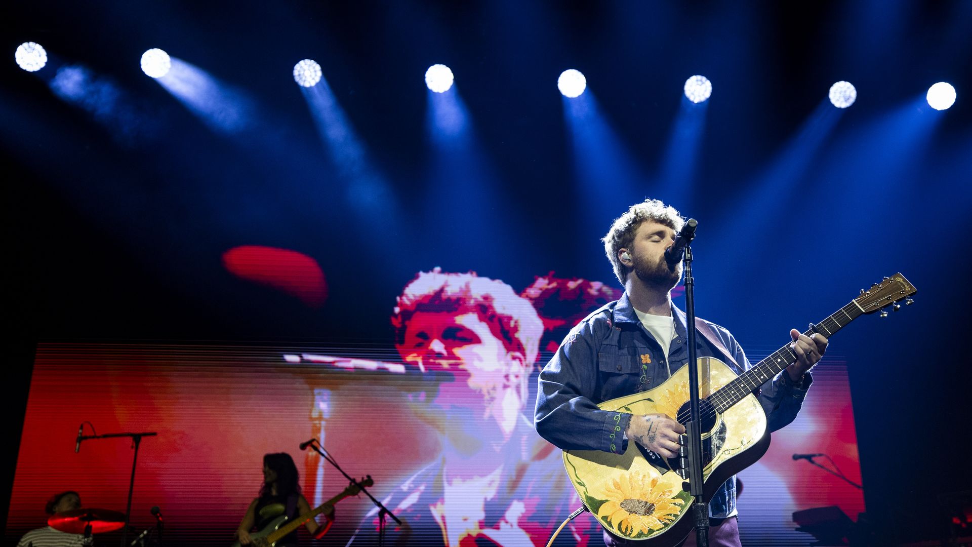 A man plays guitar and sings on a stage.