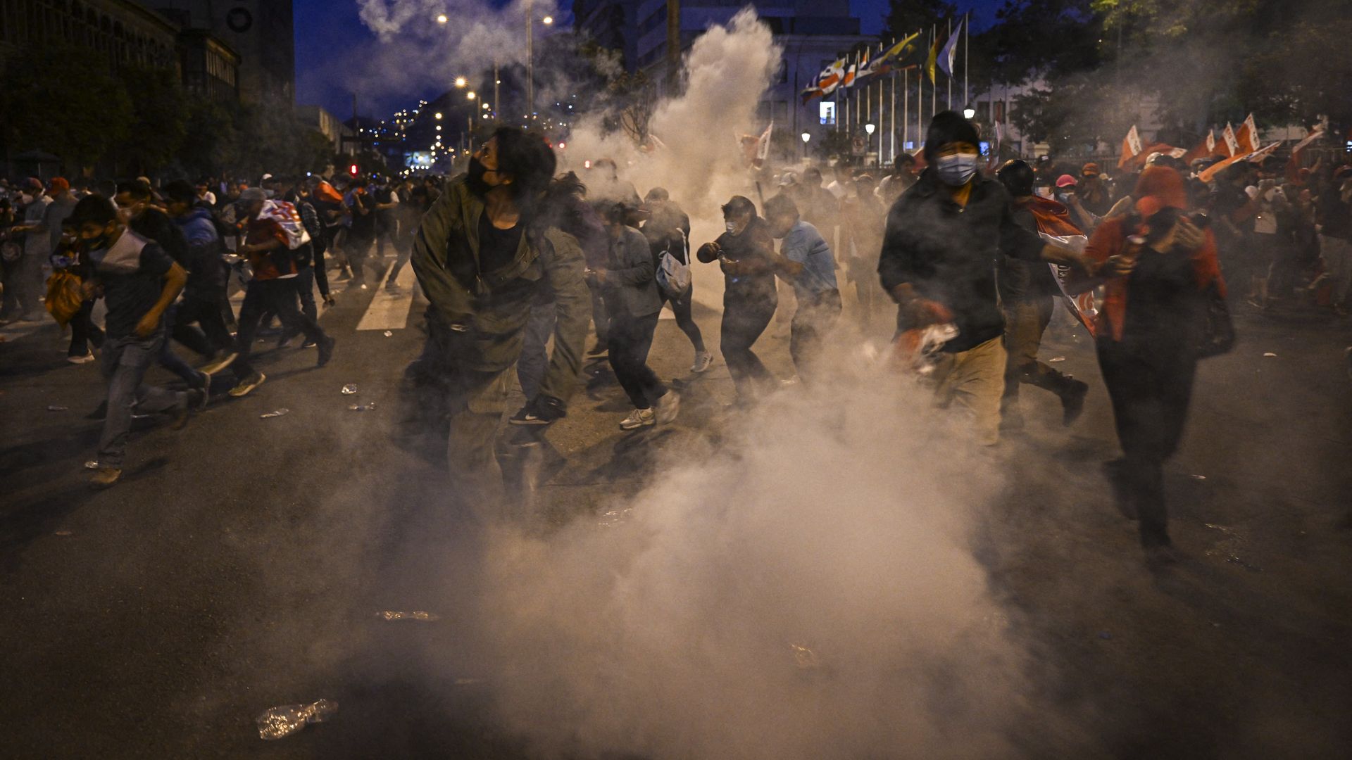 Supporters of ex-President Pedro Castillo take cover from police tear gas during clashes in Lima, on December 11.