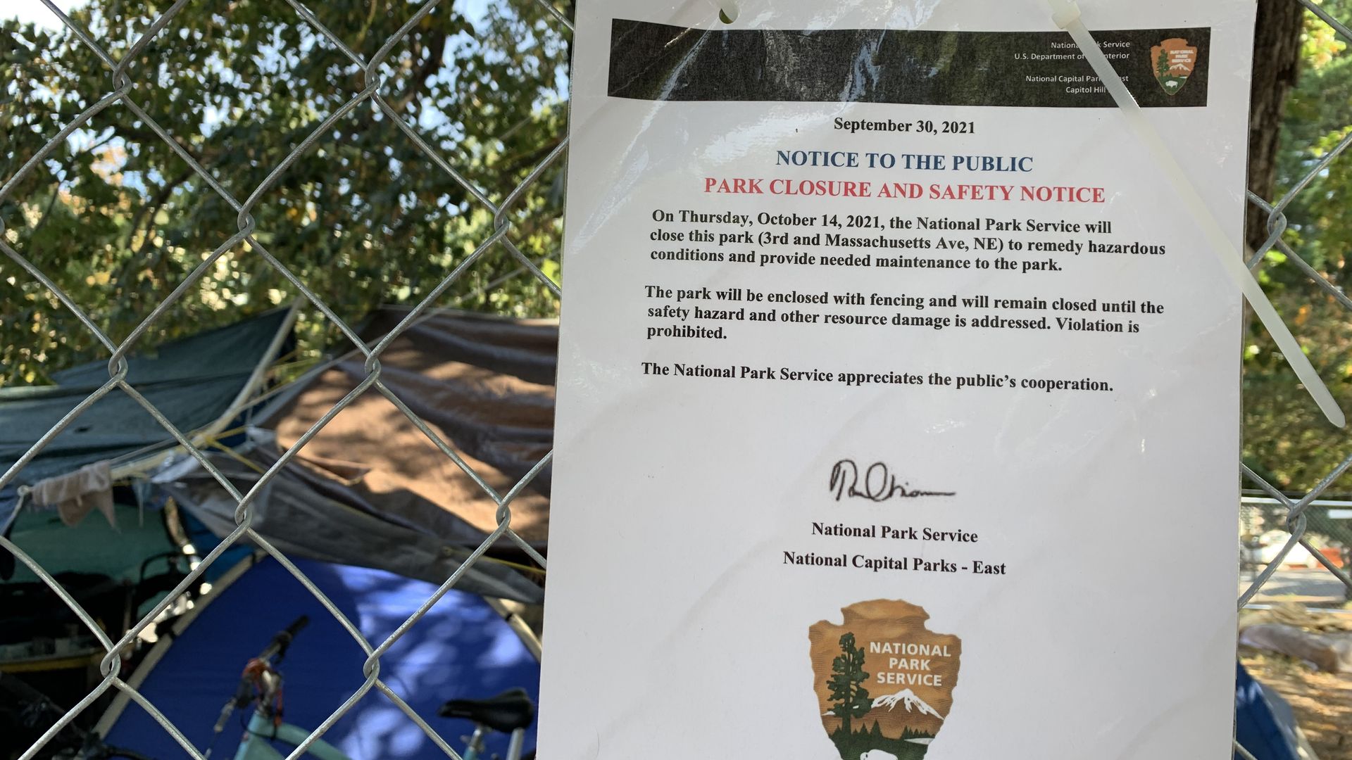 A sign attached to a fence detailing encampment clearing info.