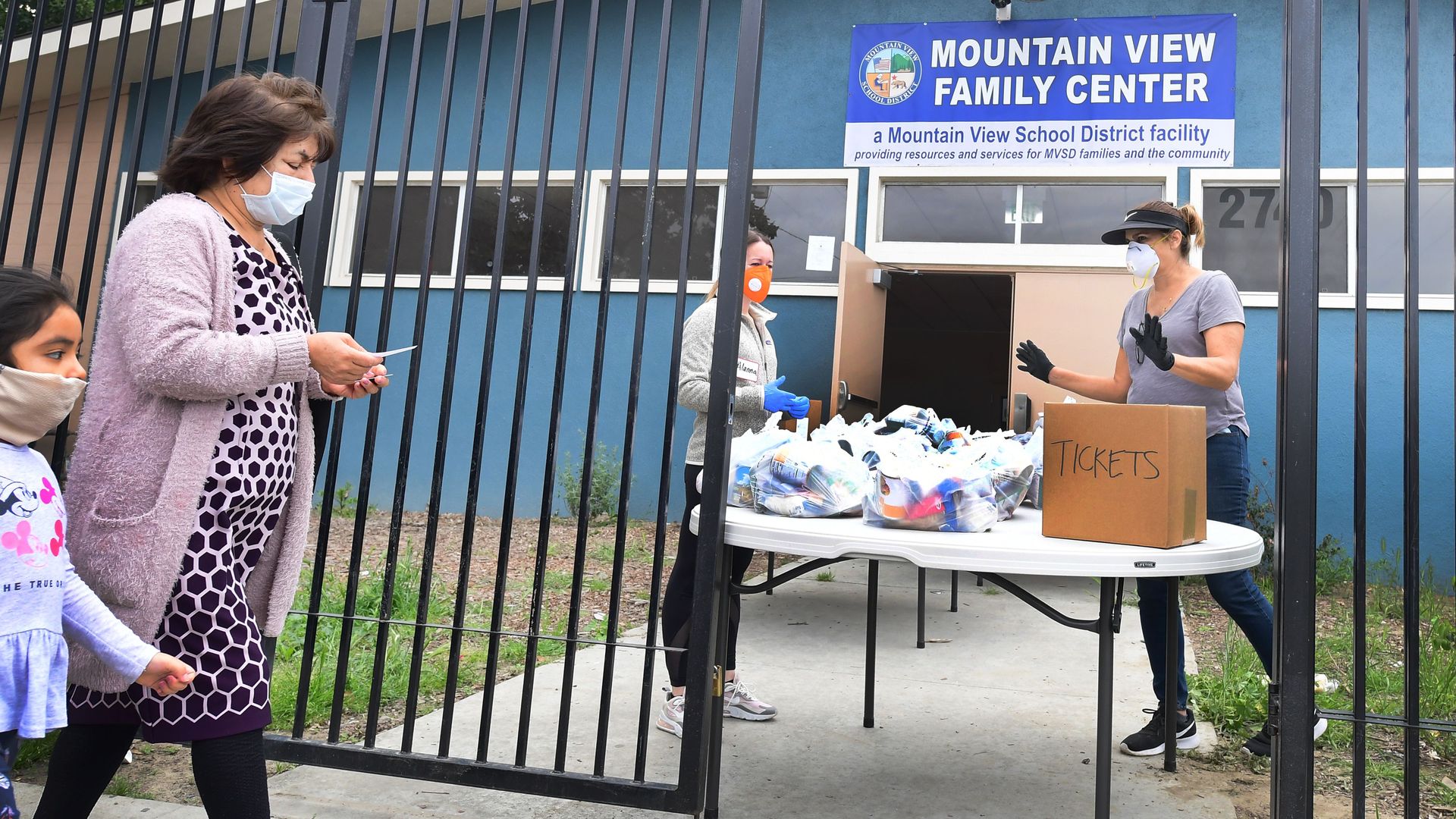In this image, a mom and her child walk past a gate to the Mountain View Family Center