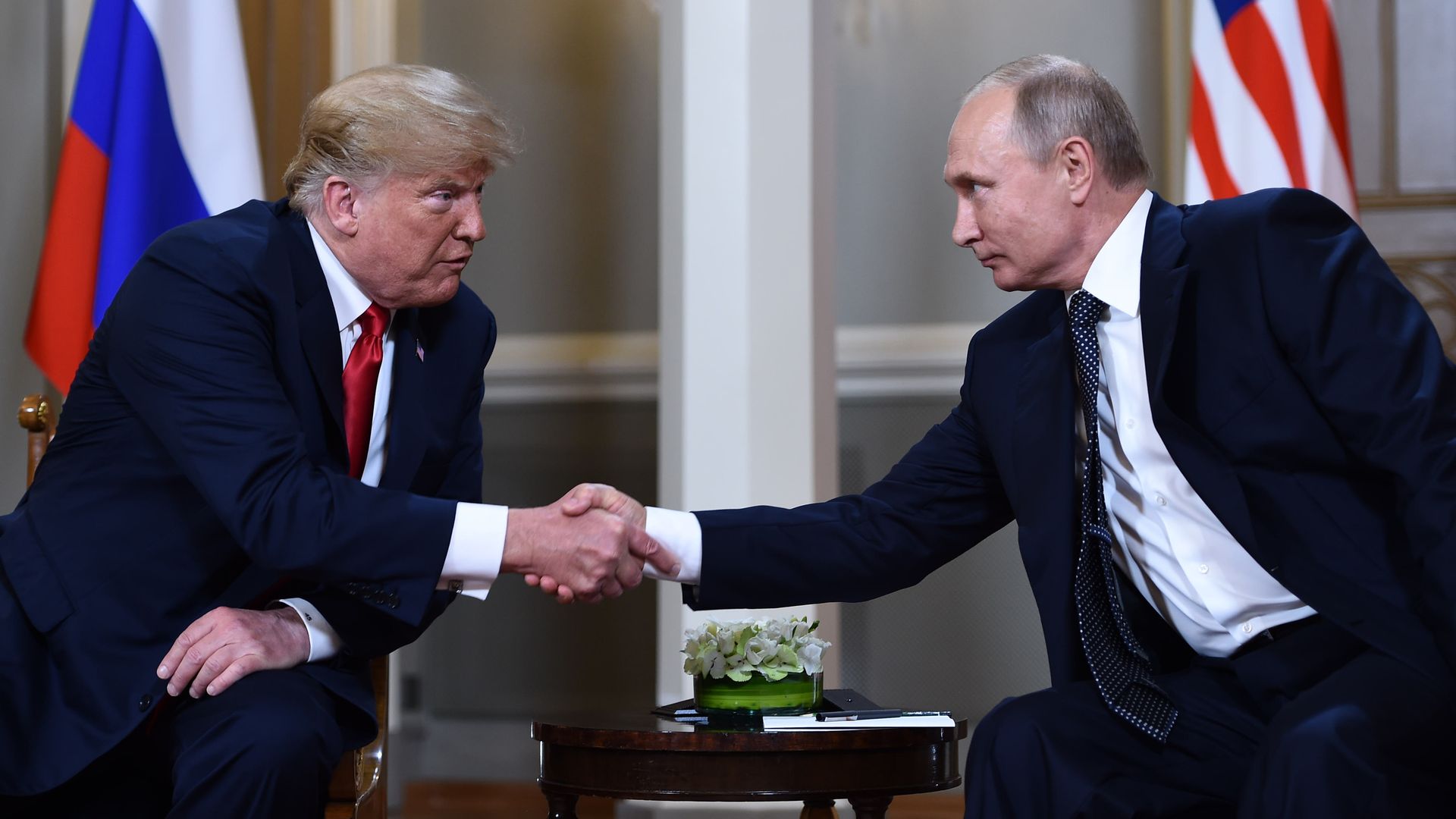 Donald Trump and Vladimir Putin shake hands.