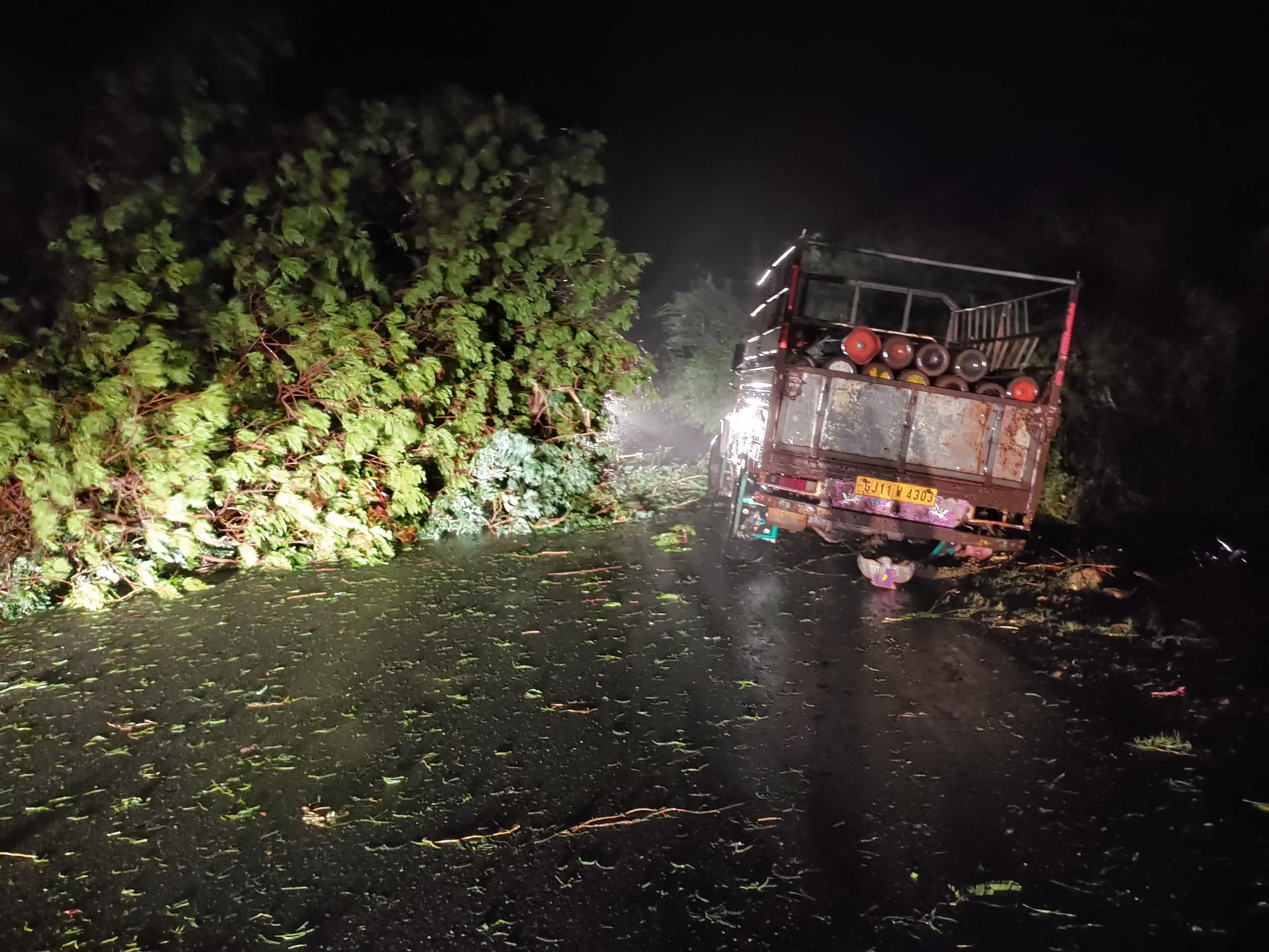 A picture taken on May 17, 2021 shows a truck loaded with oxygen cylinders stuck as trees fell due to impact of approaching Cyclone Tauktae, near Mahuva, in Gujarat state, western India. 