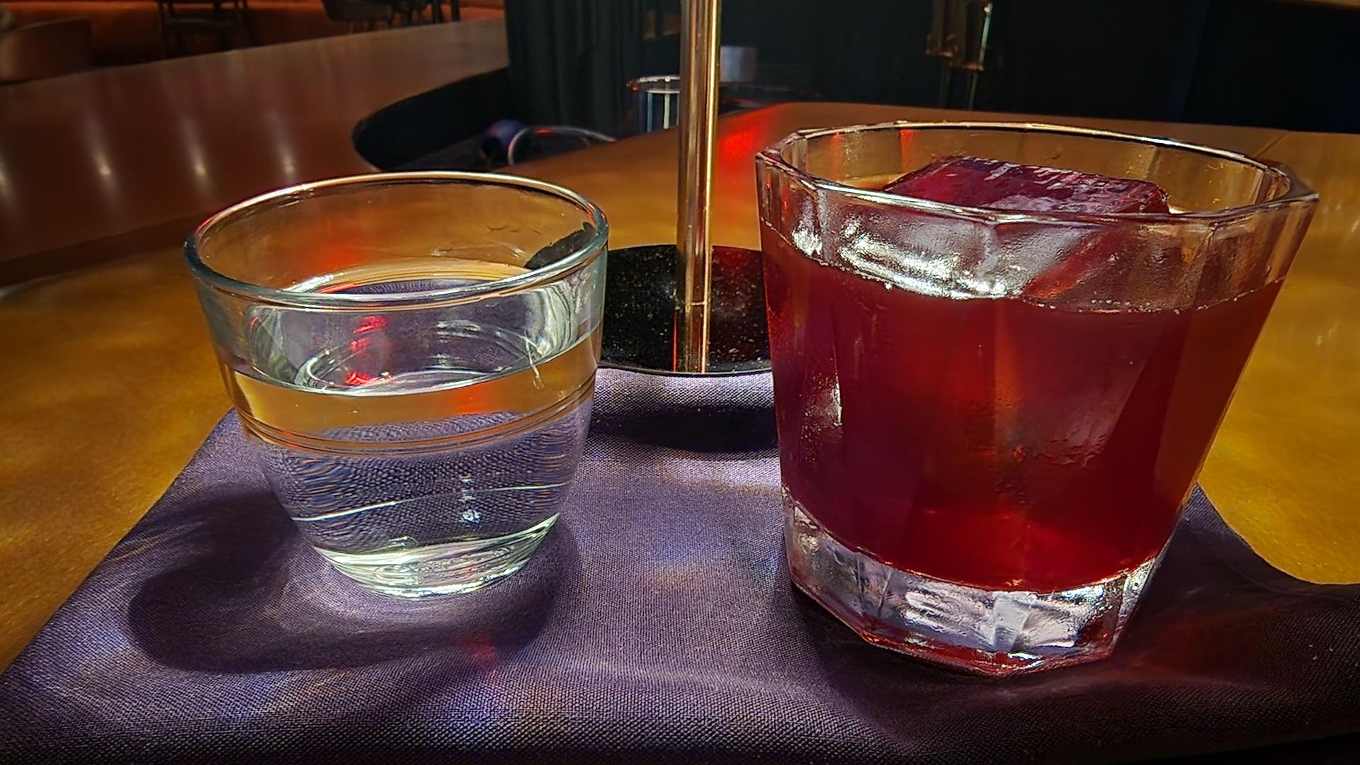 From left, a glass of water and a cocktail called Black Moon Rising, which has condesa prickly pear, acidified raspberry, ruby port and sage atomic black at Foxglove Terrace in the Atlas Hotel in Brighton.