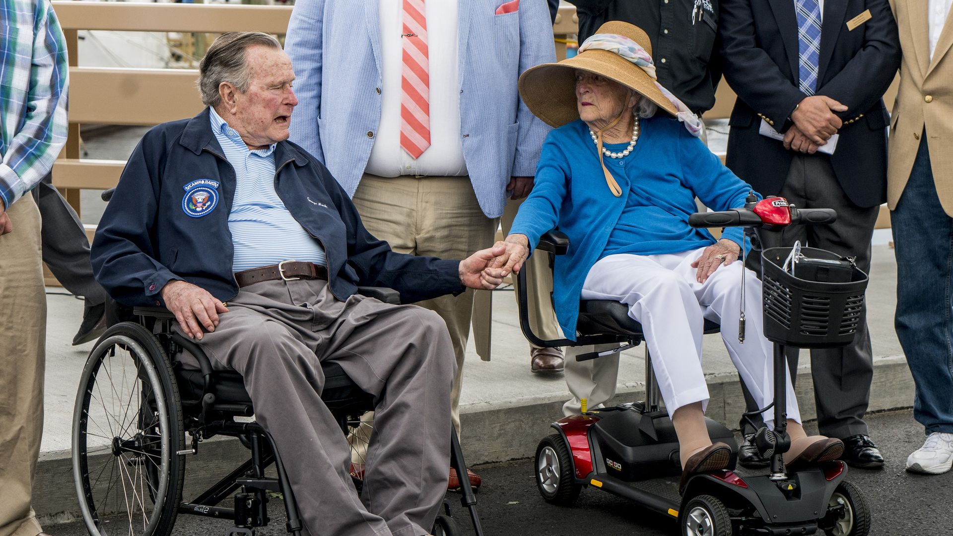 Former President George H.W. Bush and first lady Barbara Bush hold hands and talk.