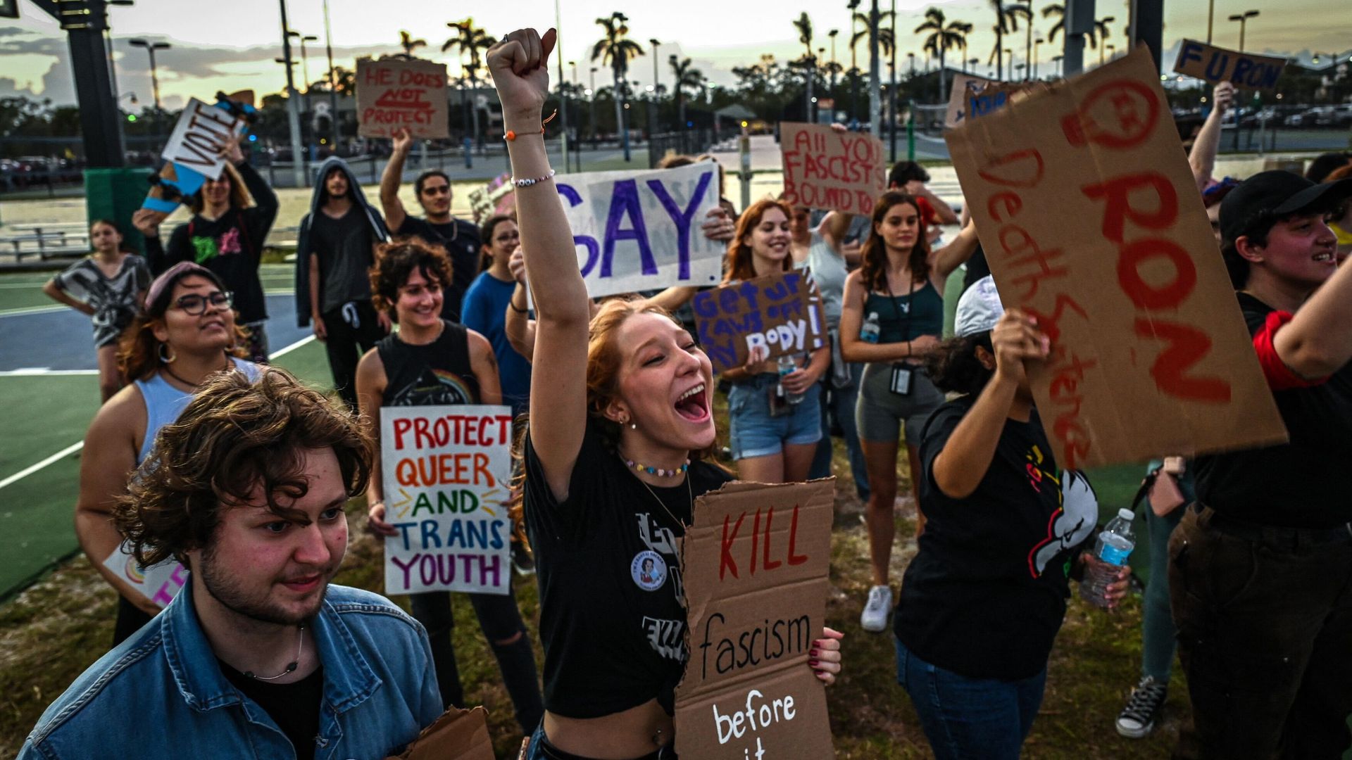 protesters holding pro LGBTQ and anti ron desantis signs