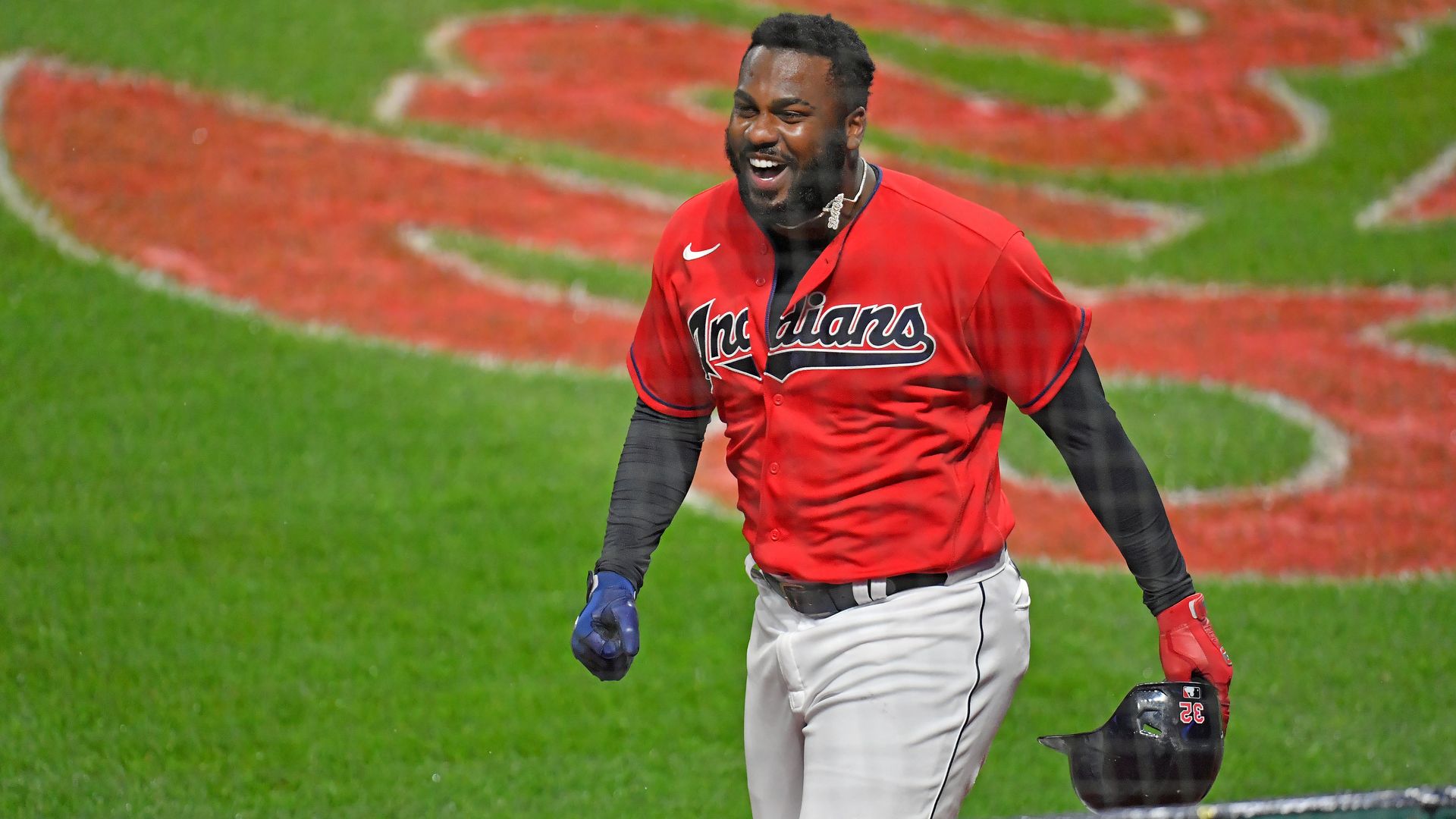A man wearing a jersey with the word "Indians" on it runs across a baseball field 