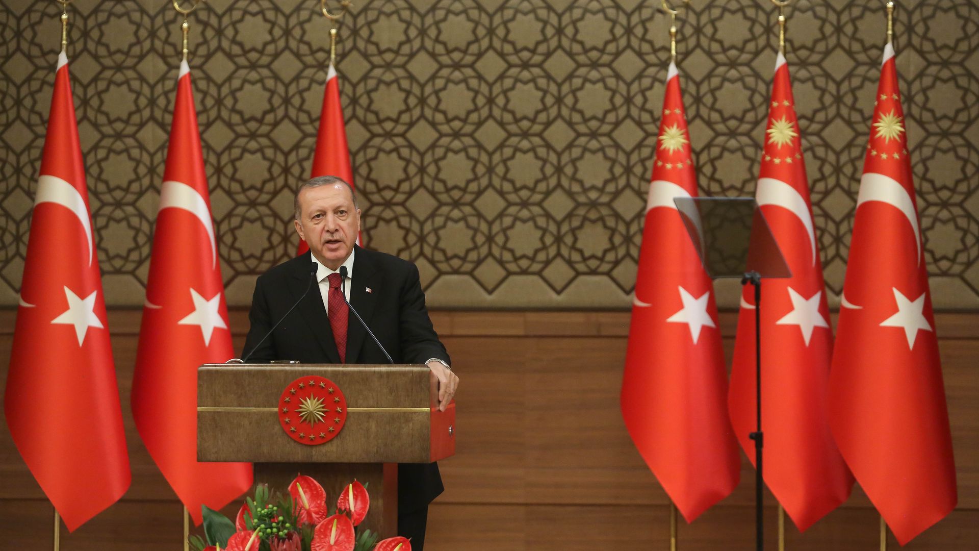 Turkey's President Erdogan giving a speech in front of Turkish flags.