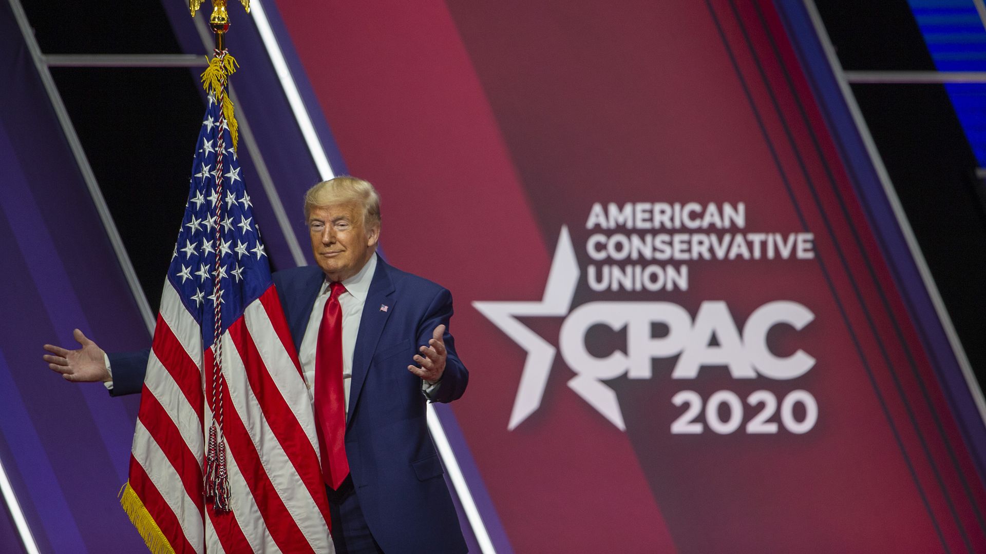 In this image, Trump stands next to a CPAC sign