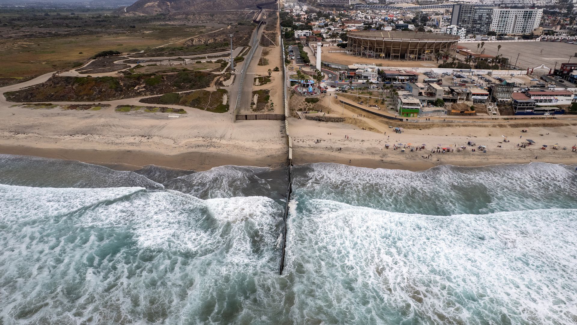 This aerial view shows the MexicoU.S. border wall extending into the Pacific Ocean at Playas de Tijuana, Baja California state, Mexico on August 12, 2025. Despite the work of a wastewater treatment plant, residents in Mexico's Tijuana see no difference in the quality of the water running through the
