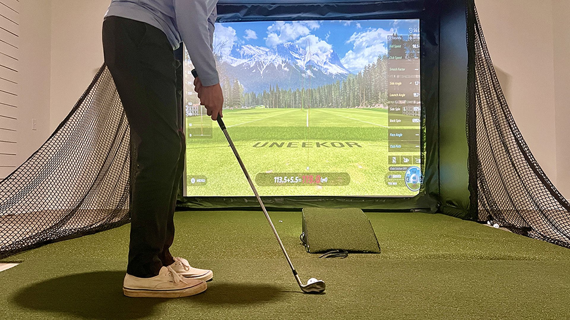 A person prepares to hit a golf ball using a golf simulator.