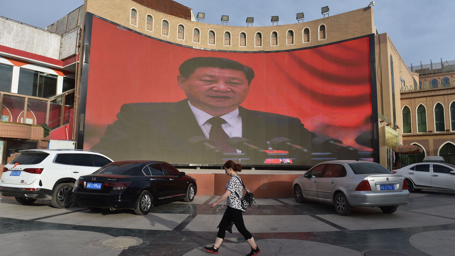 This photo taken on June 4, 2019 shows people walking past a screen showing images of Chinese President Xi Jinping in Kashgar, in China's western Xinjiang region.