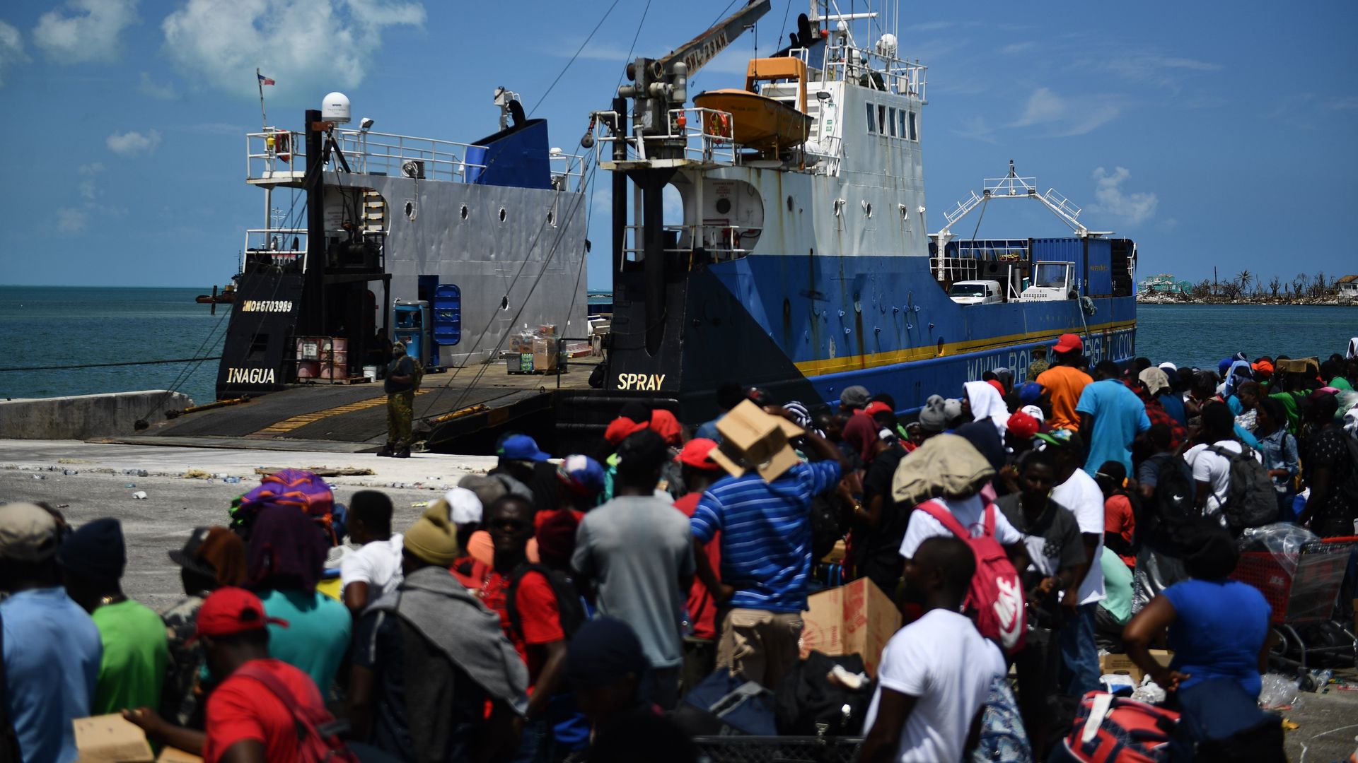 People wait to board a cargo ship for evacuation to Nassau at the port after Hurricane Dorian September 7, 2019, in Marsh Harbor, Great Abaco.