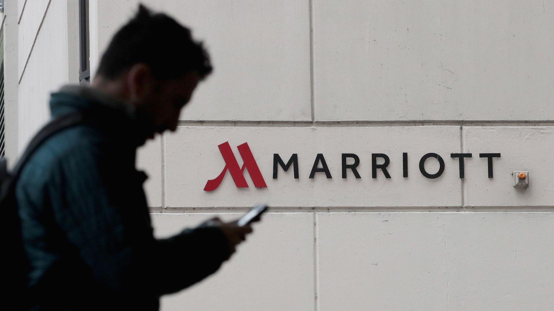 A man walks by the Marriott logo