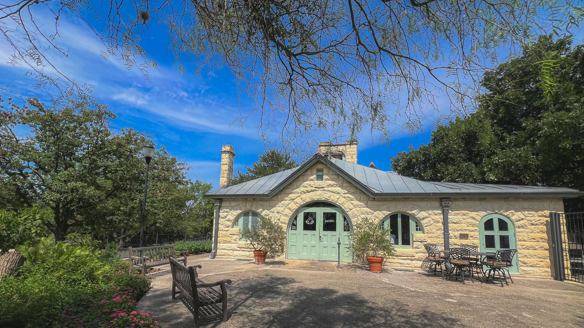 A cottage-style building with teal accents nestled among trees 