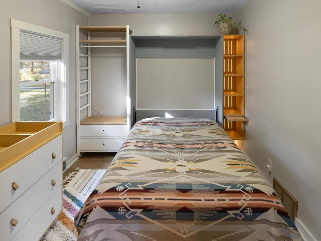 A bedroom with shelving and a colorful bed.