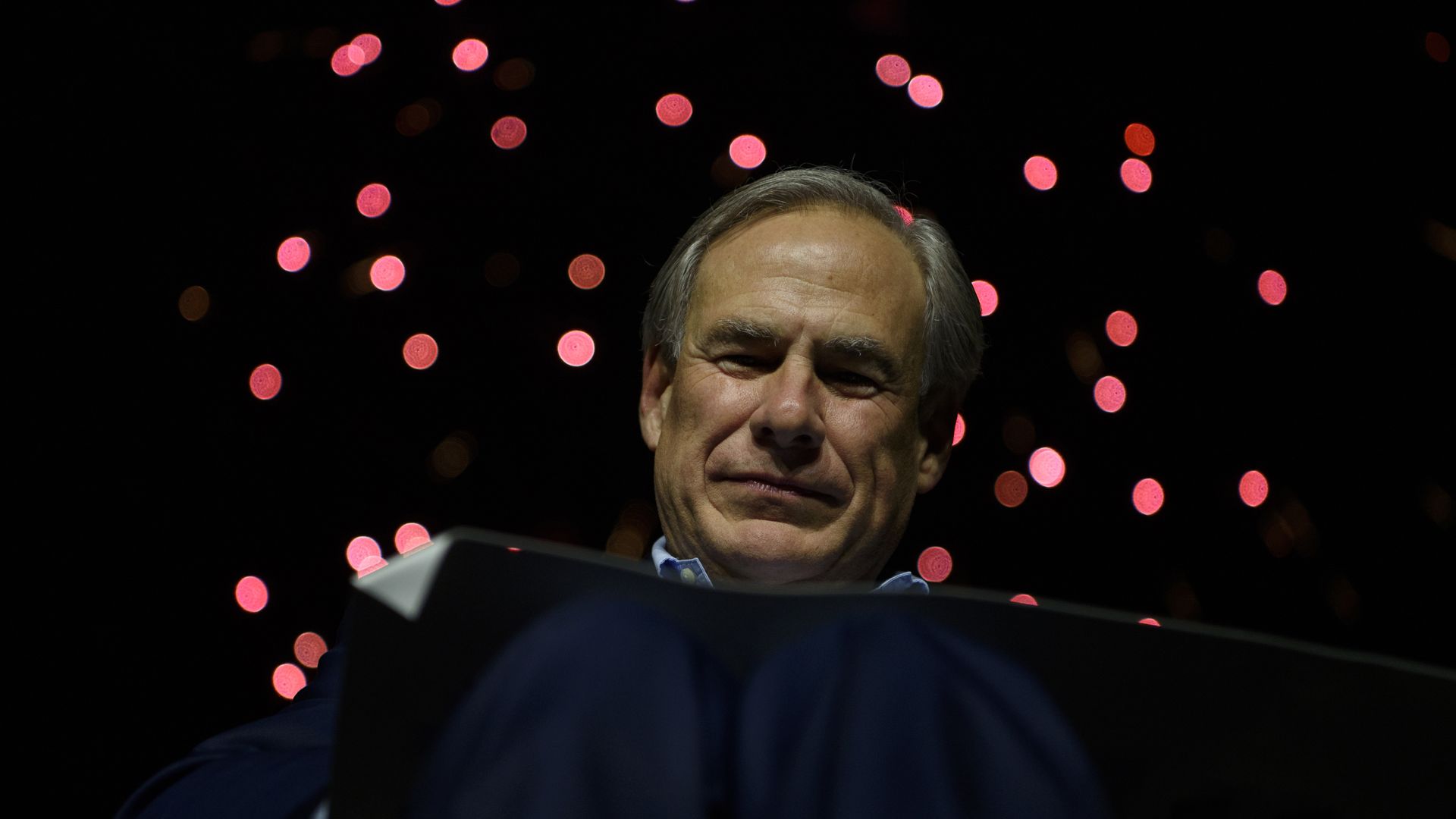 Texas Gov. Greg Abbott's face is visible behind a lectern 