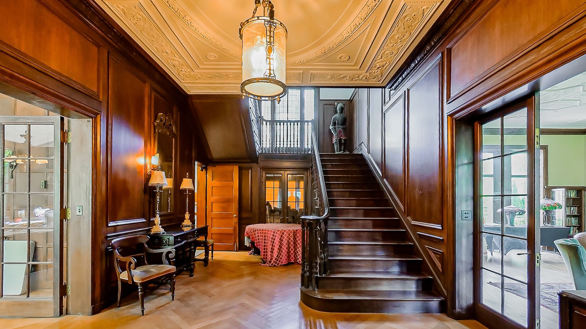 Luxurious foyer with dark wood paneling and an ornate staircase.
