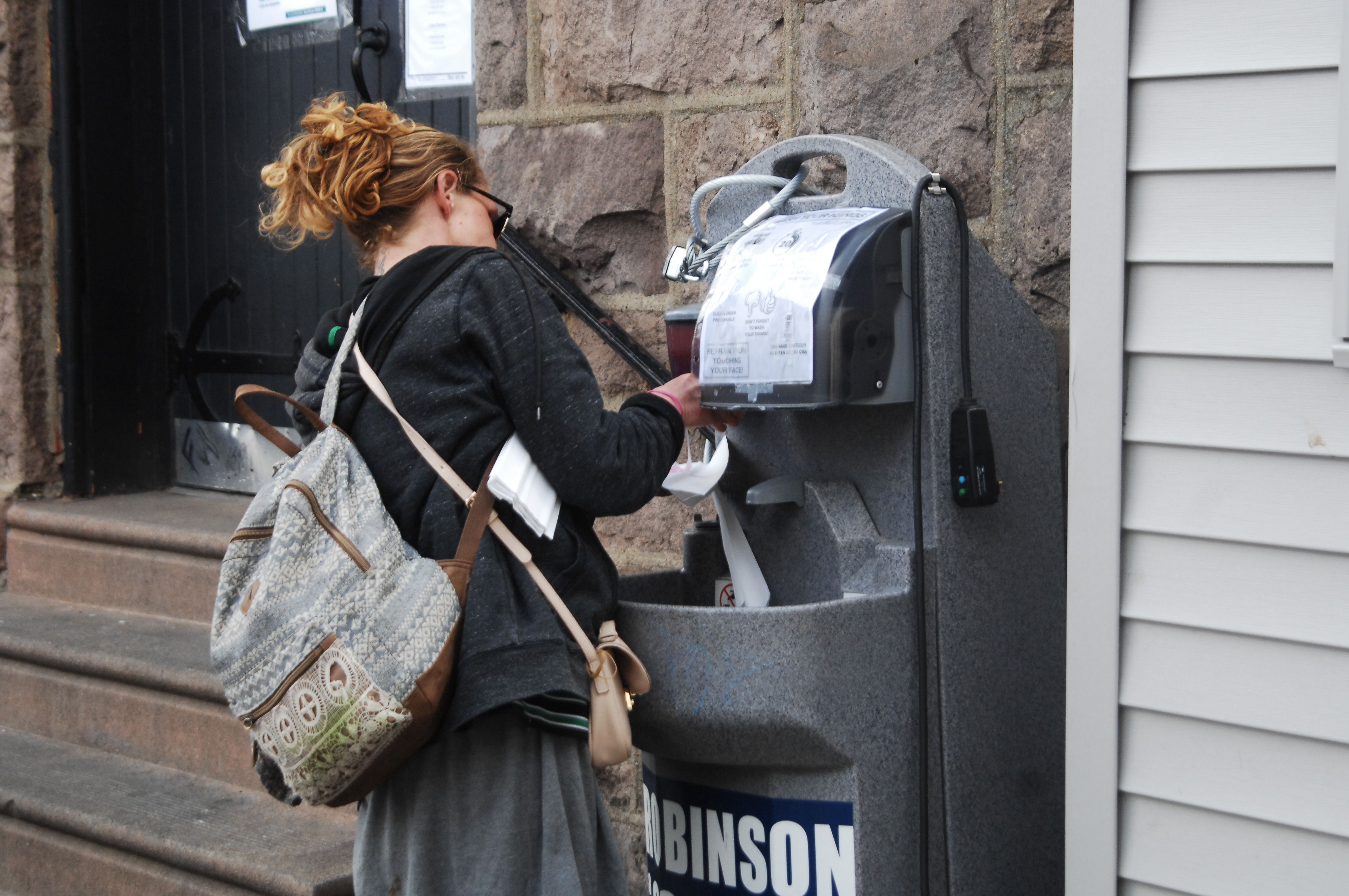 A young homeless woman washes her hands at a sanitation station outside a mission in the Kensington of Philadelphia, PA