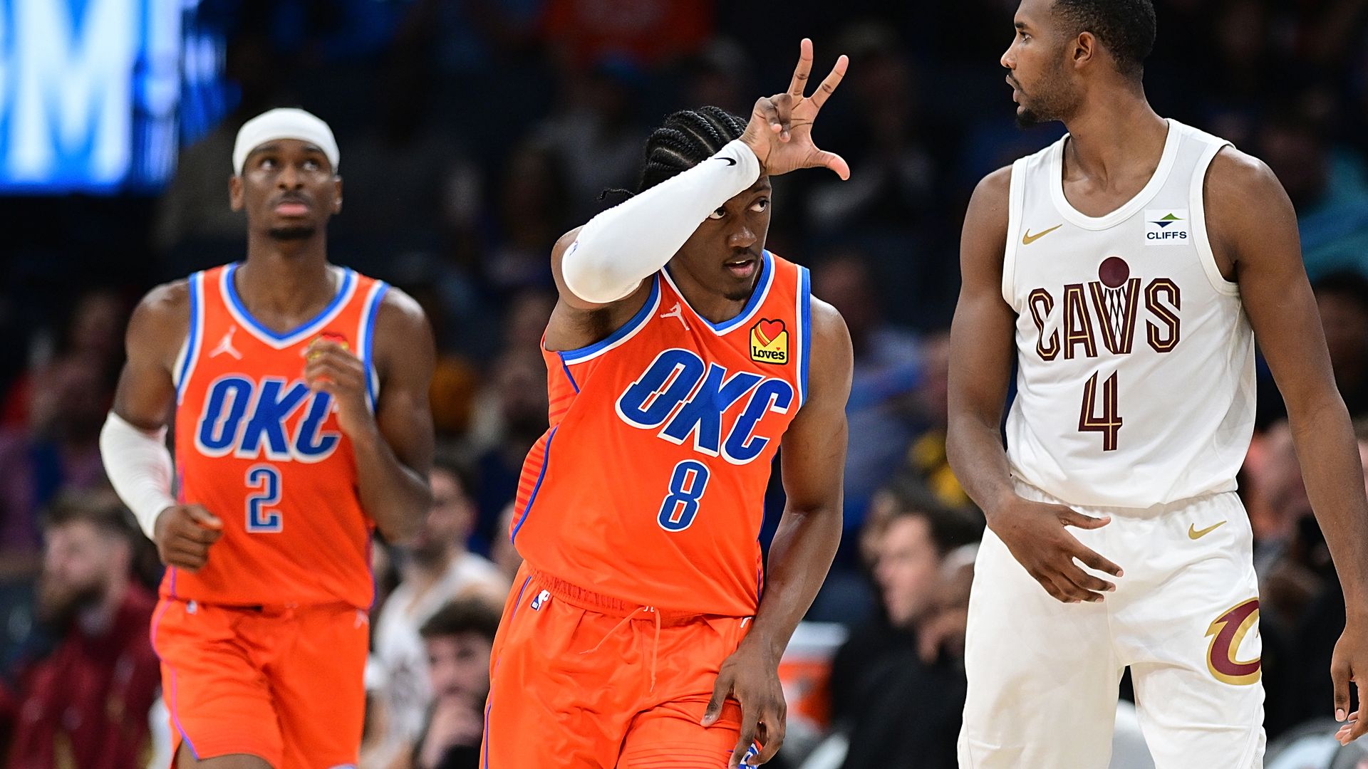 Two Thunder players in Orange jerseys and Evan Mobley in white Cavs jersey