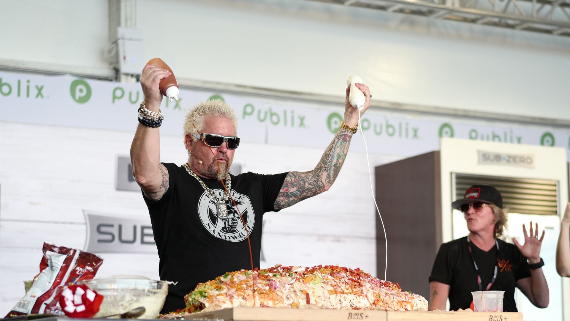 A man in sunglasses pours sauce on a giant burrito 