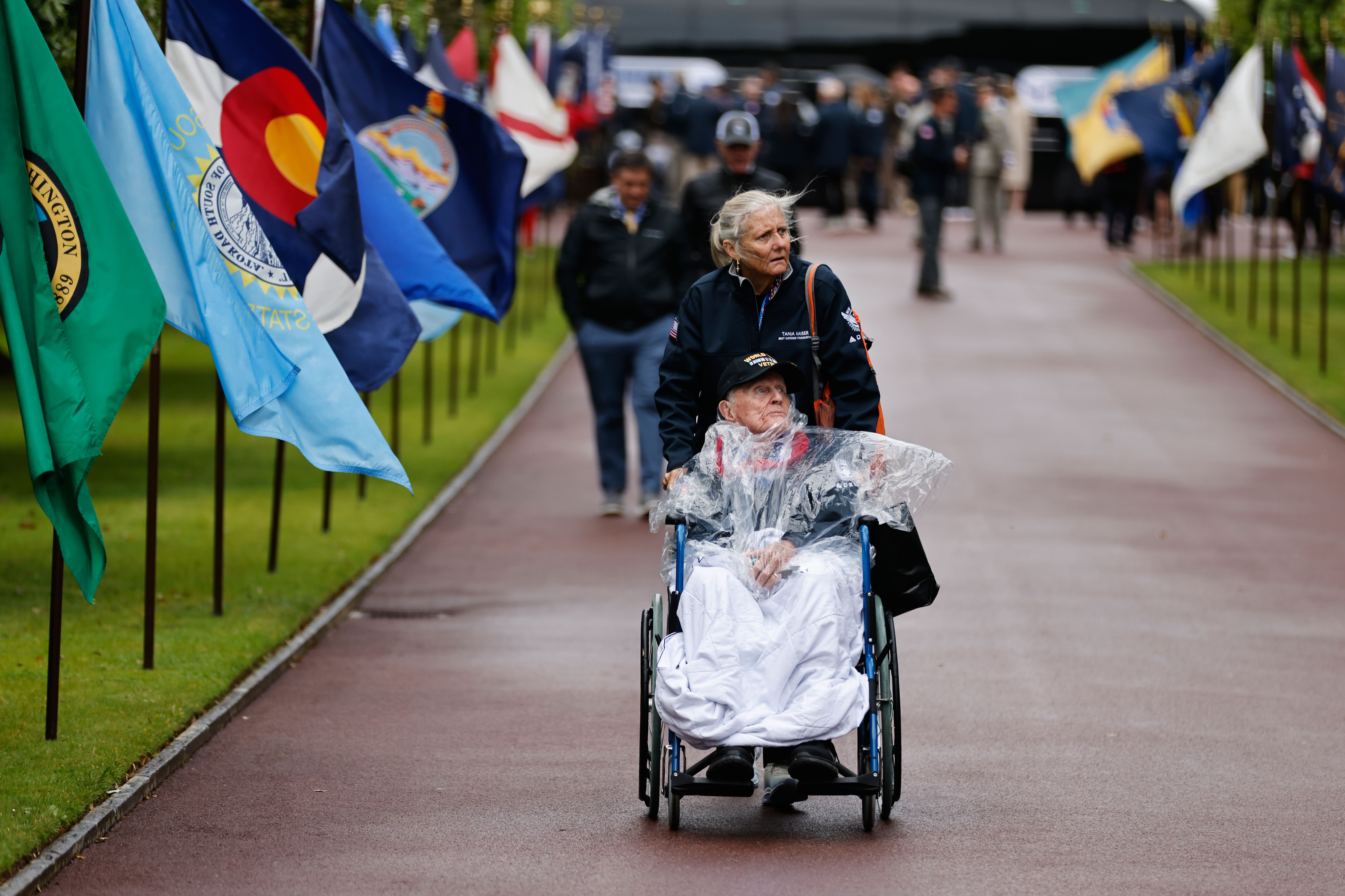 A person escorts a war veteran through a cemetery