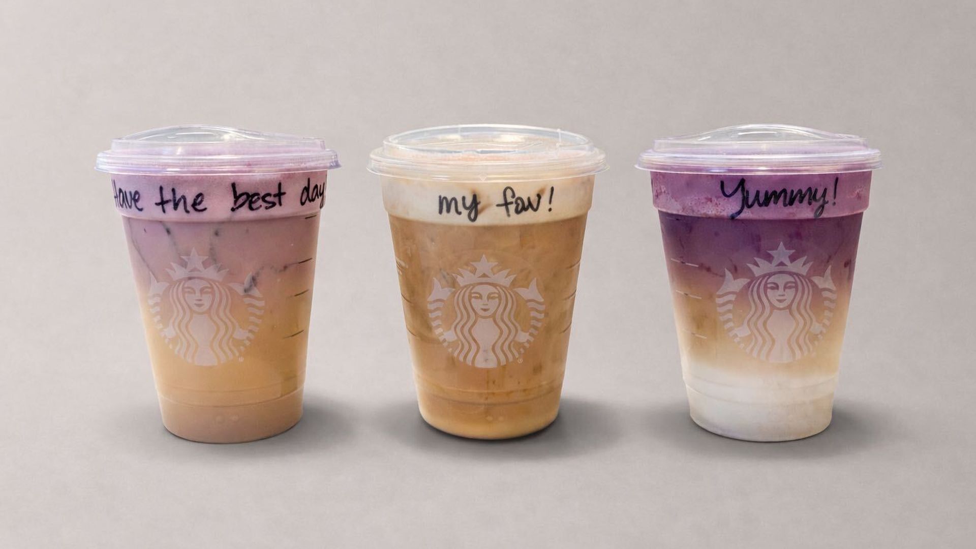 Three Starbucks iced drinks with handwritten messages on lids: "Have the best day," "my fav!", and "Yummy!", featuring purple, beige, and white layered colors.