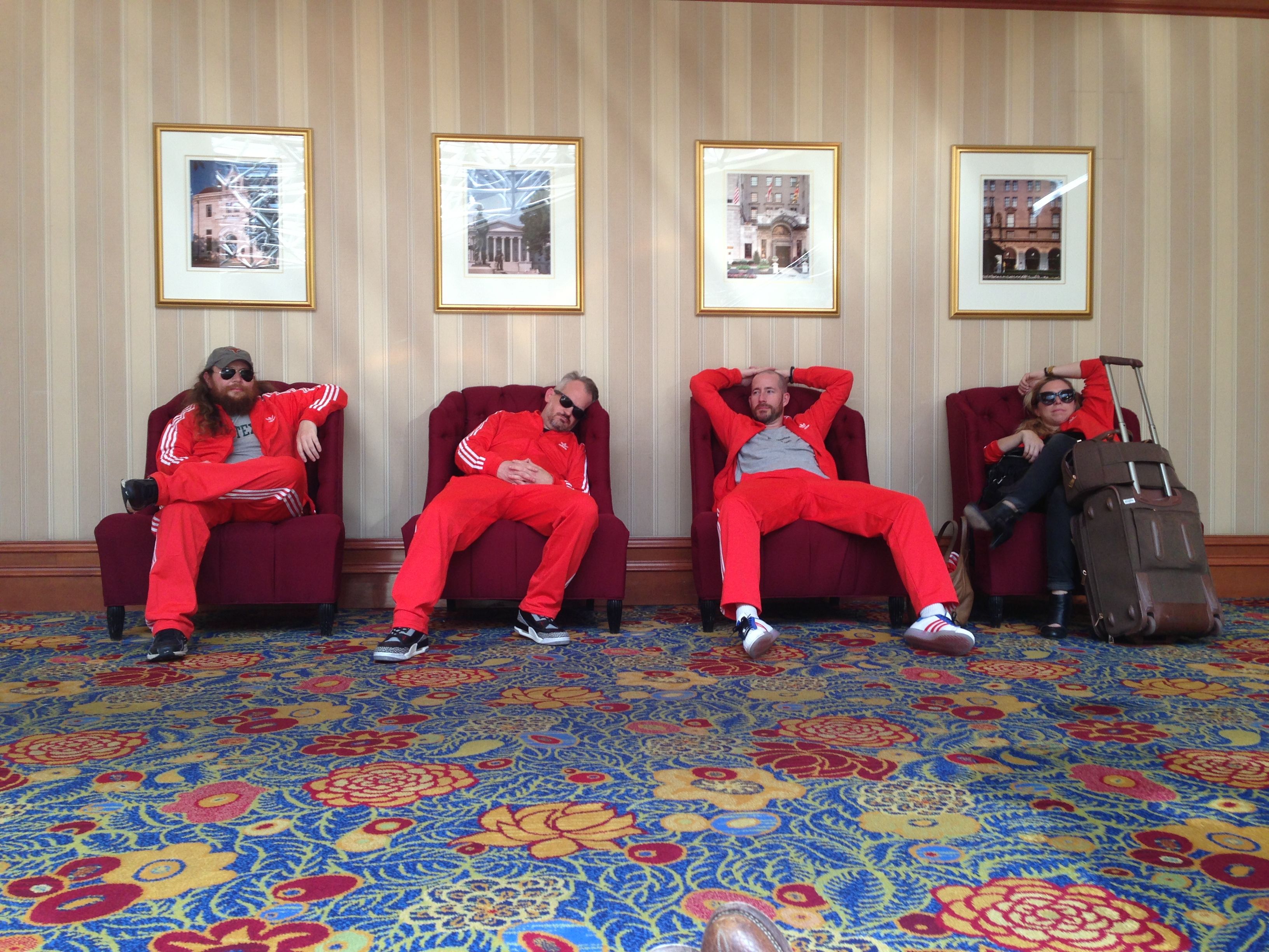 Four people in red track suits looking very tired in a hotel lobby
