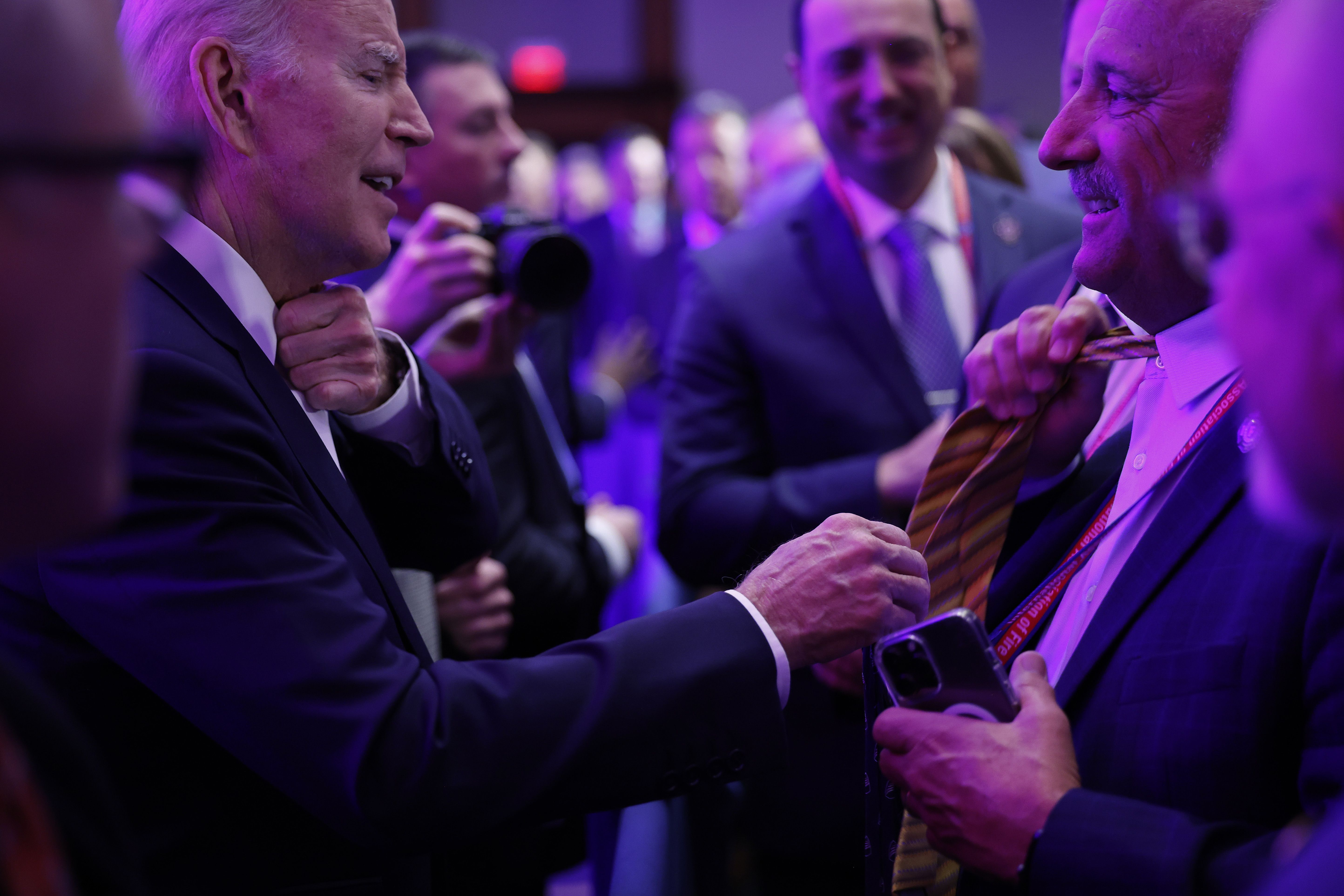 President Biden removes his necktie Monday to trade it with a firefighter during the International Association of Fire Fighters' legislative conference on Capitol Hill.