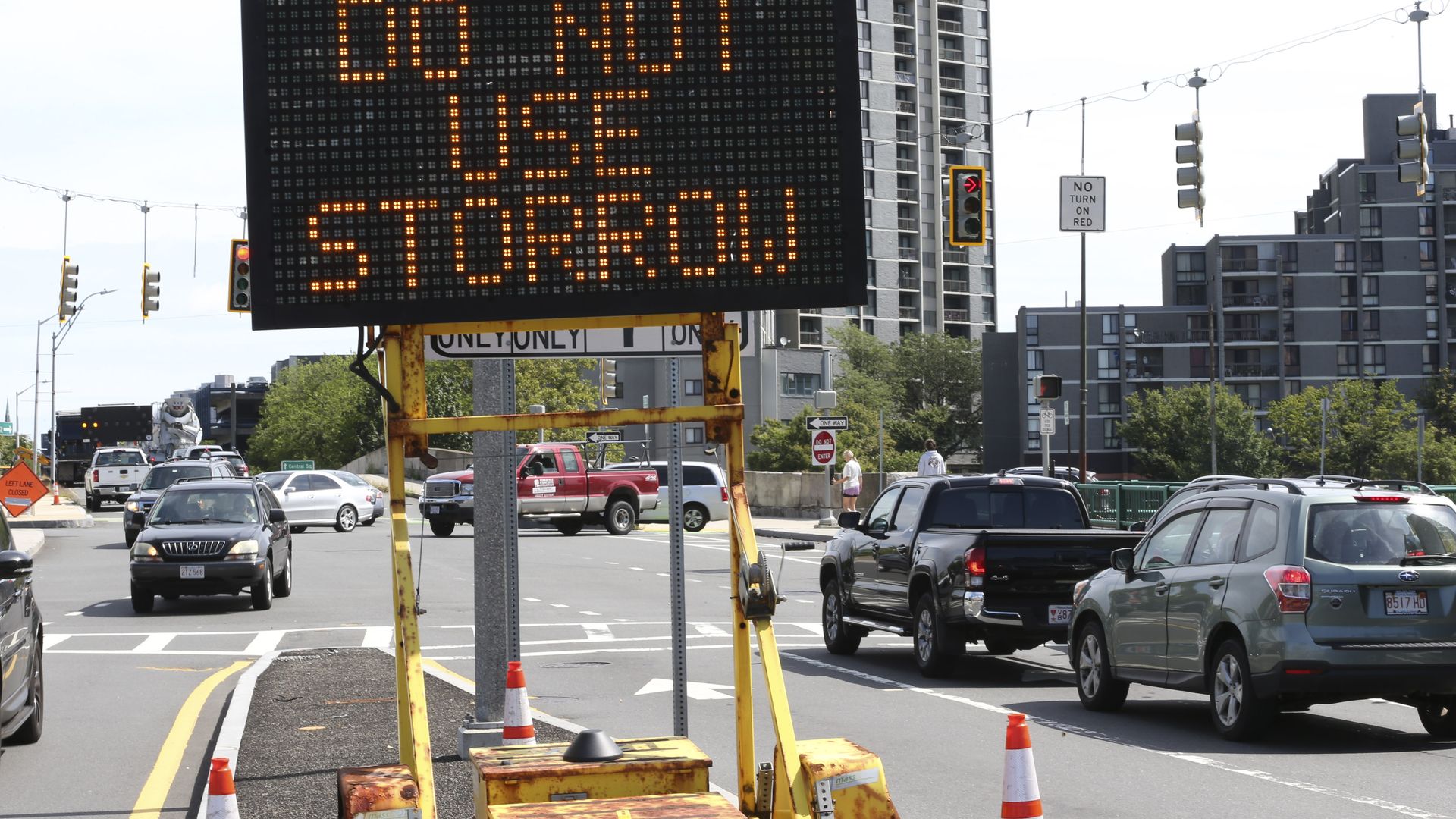 An electronic traffic sign reads "Do not use storrow" on the median as cars wait at a red light. 