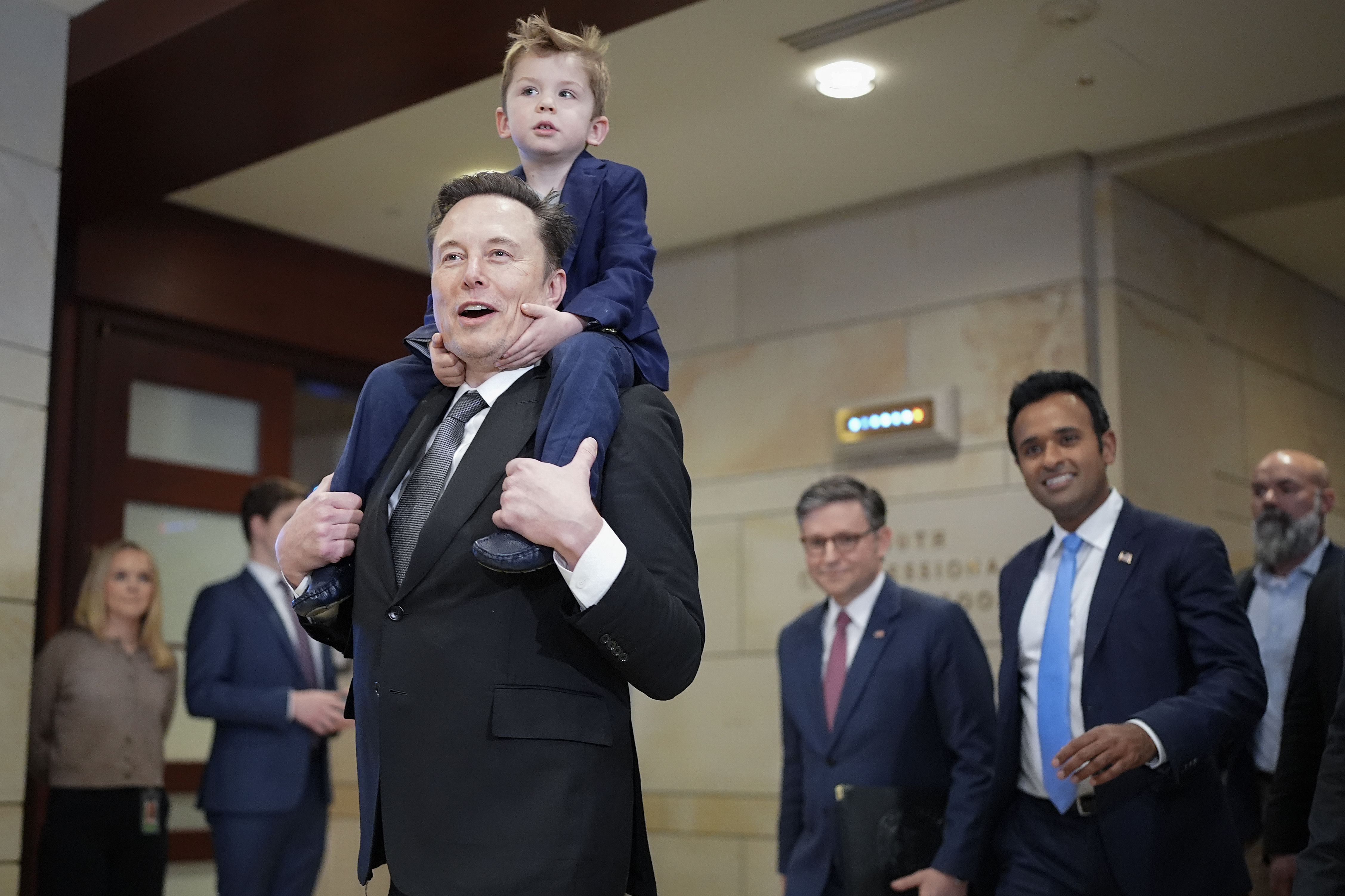 Tesla CEO Elon Musk, Co-Chair of the newly announced Department of Government Efficiency (DOGE) carries his son on his shoulders at the U.S. Capitol after a media availability with businessman Vivek Ramaswamy (2nd R), Co-Chair of the newly announced Department of Government Efficiency and Speaker of