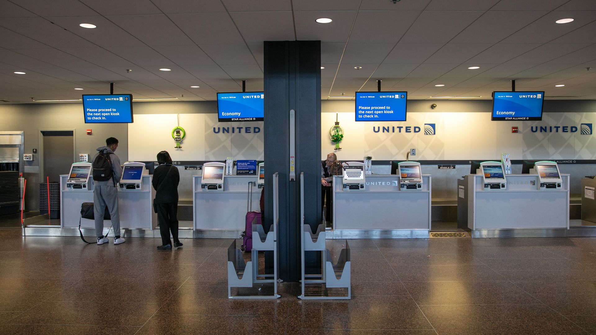 In this image, two people check luggage at a United Airlines counter.