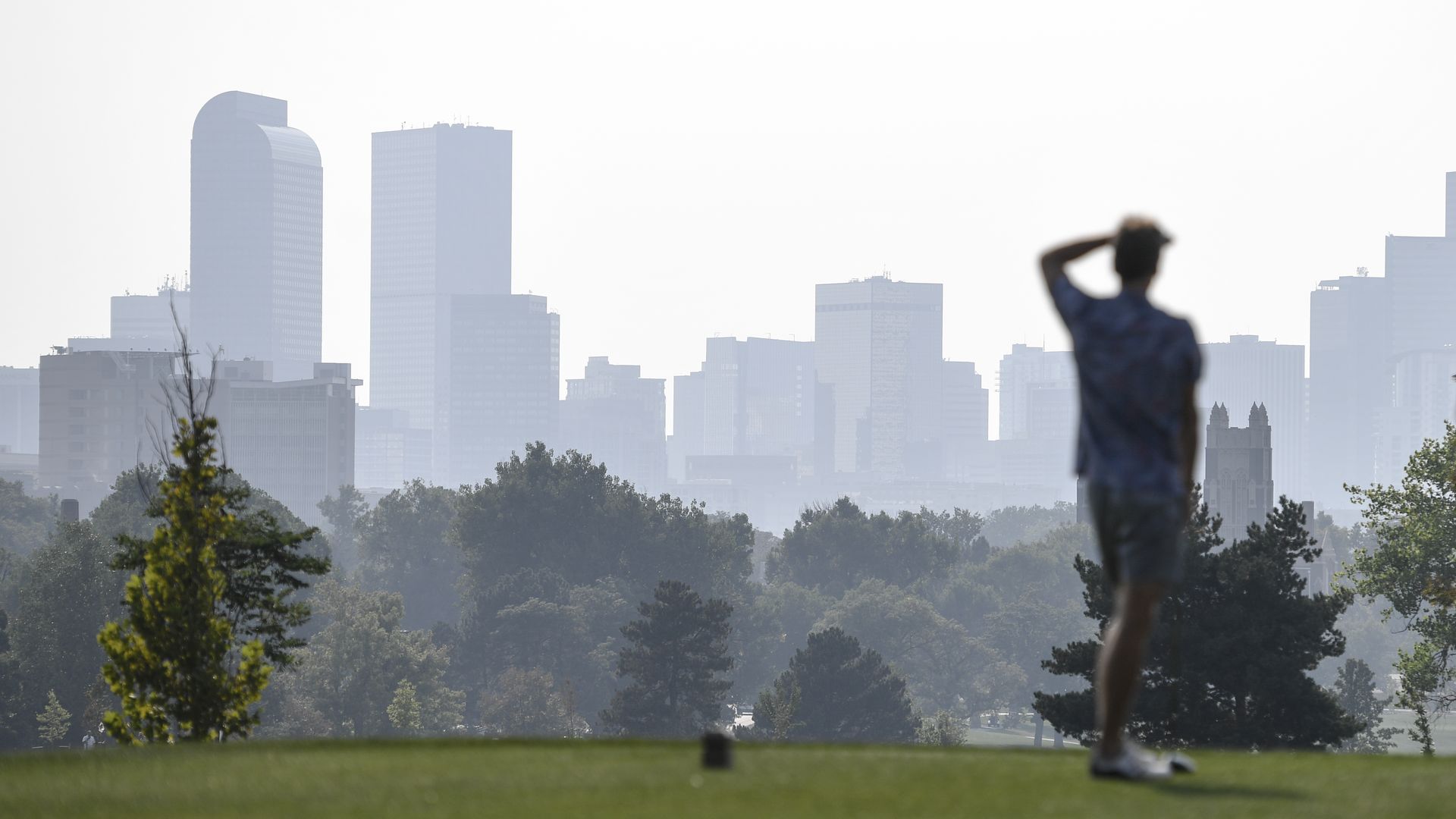 A golfer at the City Park Golf Course in September 2021 as haze clouds downtown. Photo: AAron Ontiveroz/Denver Post via Getty Images