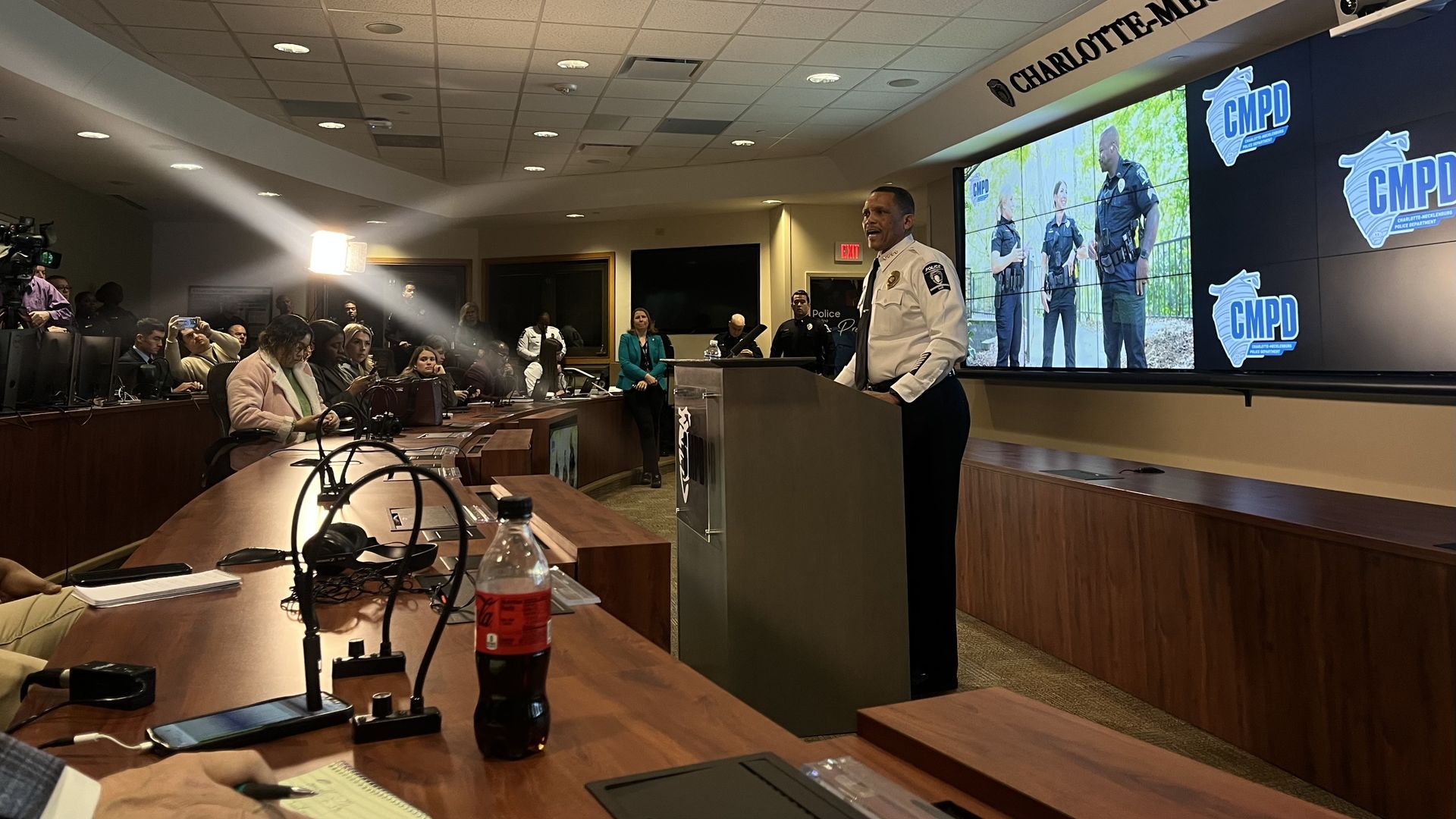 CMPD Chief Johnny Jennings stands behind a podium with a CMPD graphic and photo behind him. Photo: Alexandria Sands/Axios